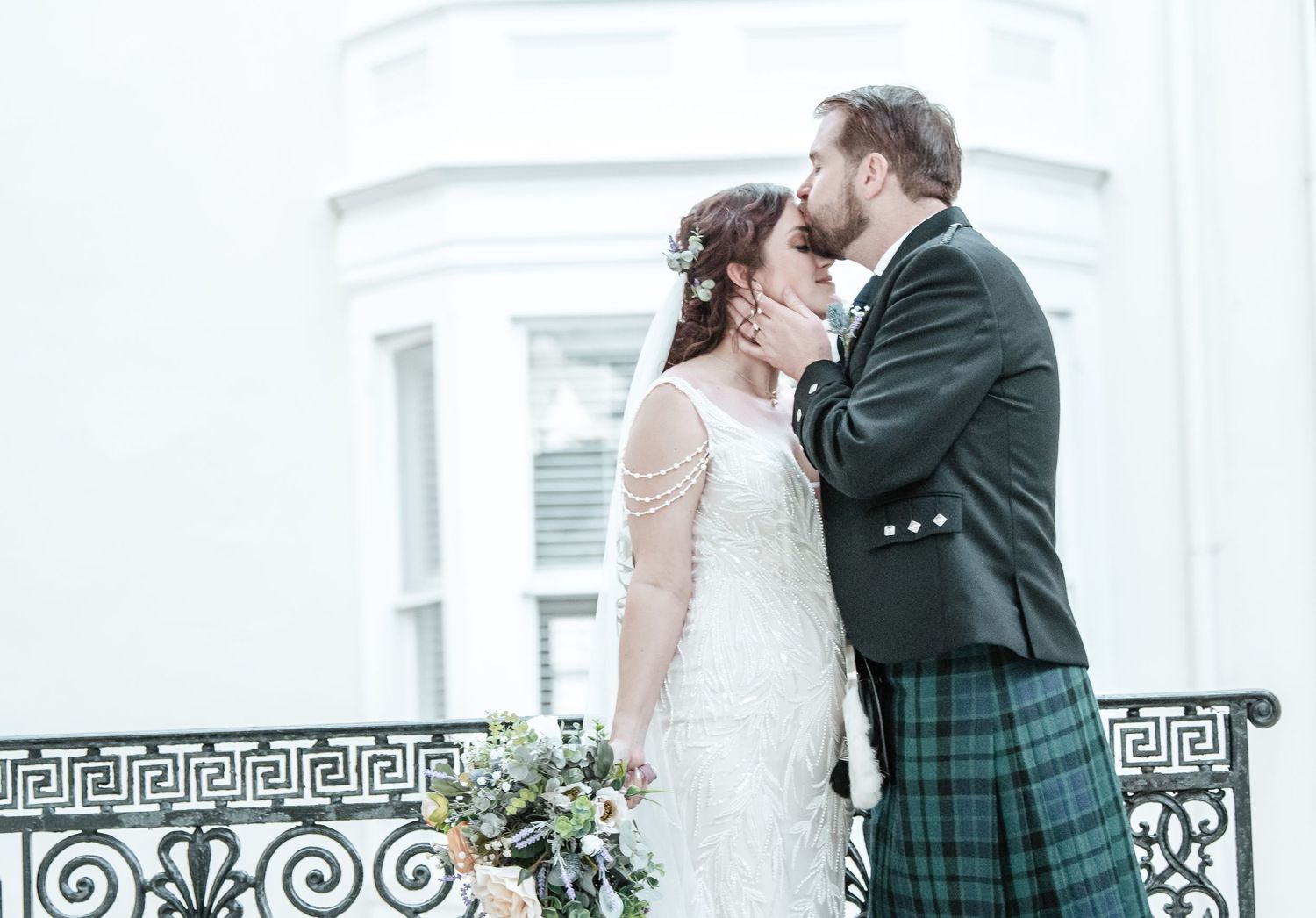 Wedding portraits against white columns with decorative Greek key pattern railings.