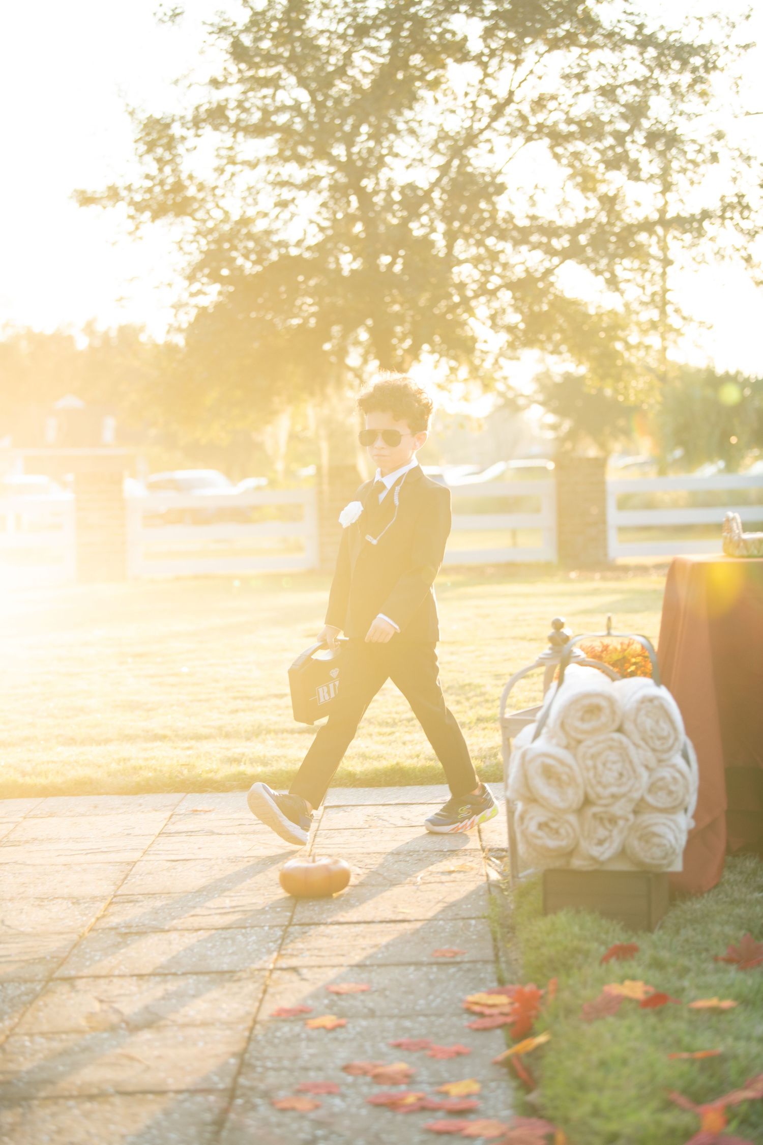 Wedding couple walks along petal-strewn path in golden sunset light.