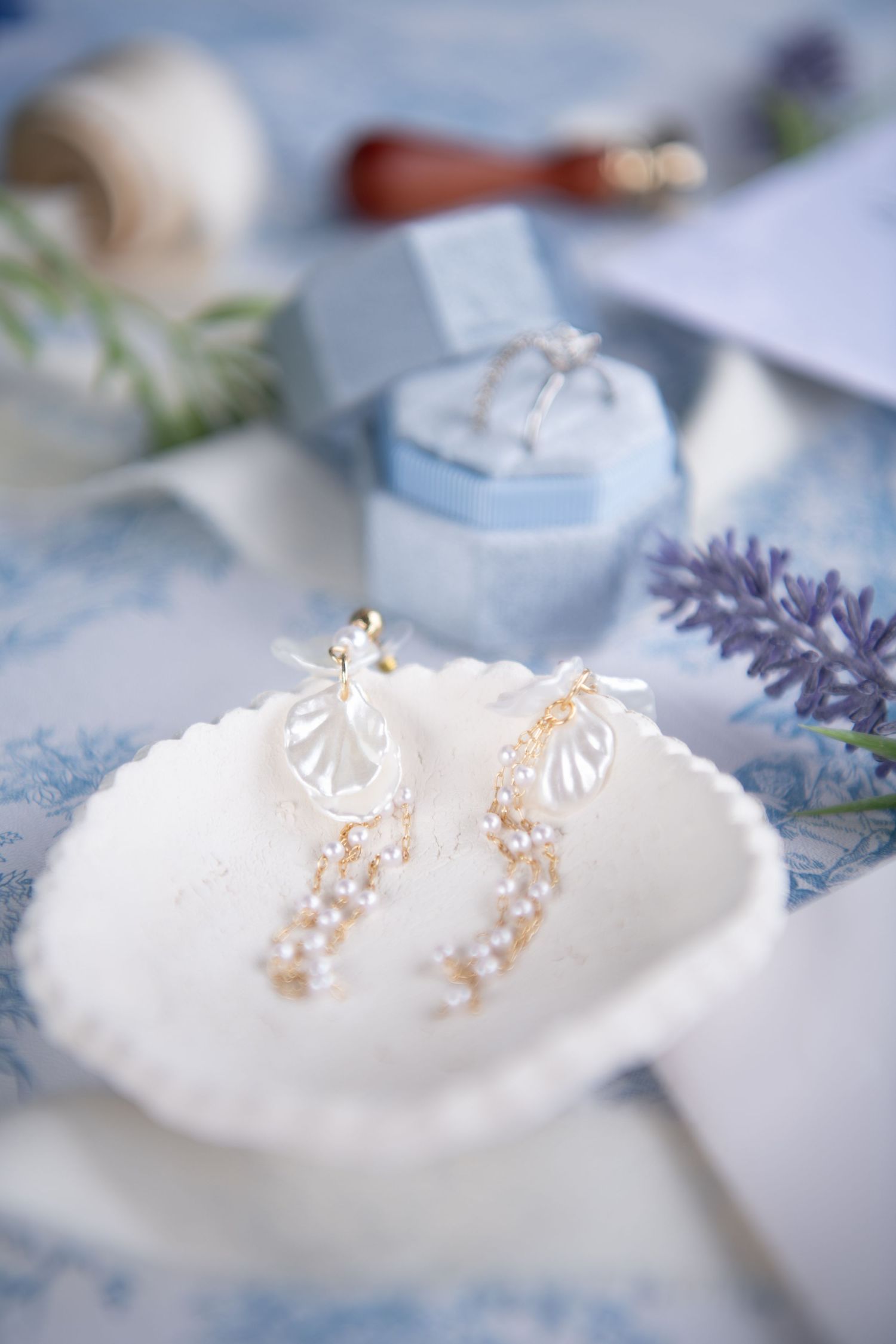 Delicate bridal jewelry displayed on white fabric with blue floral pattern.