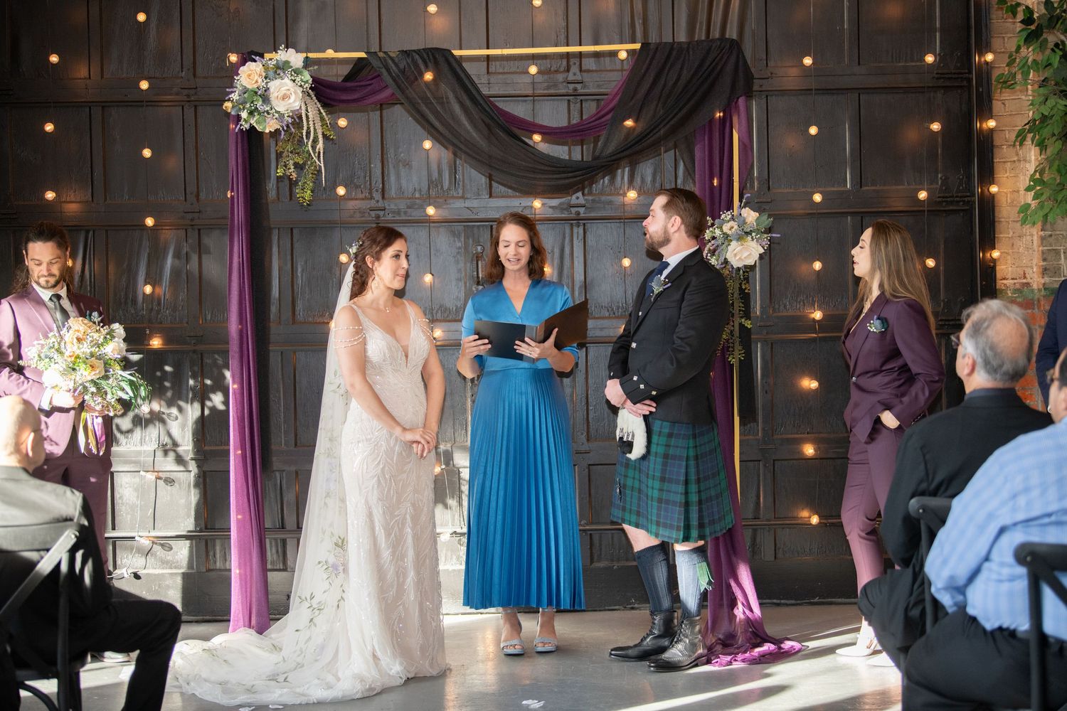 Wedding reception in a decorated venue with string lights and elegant draping.