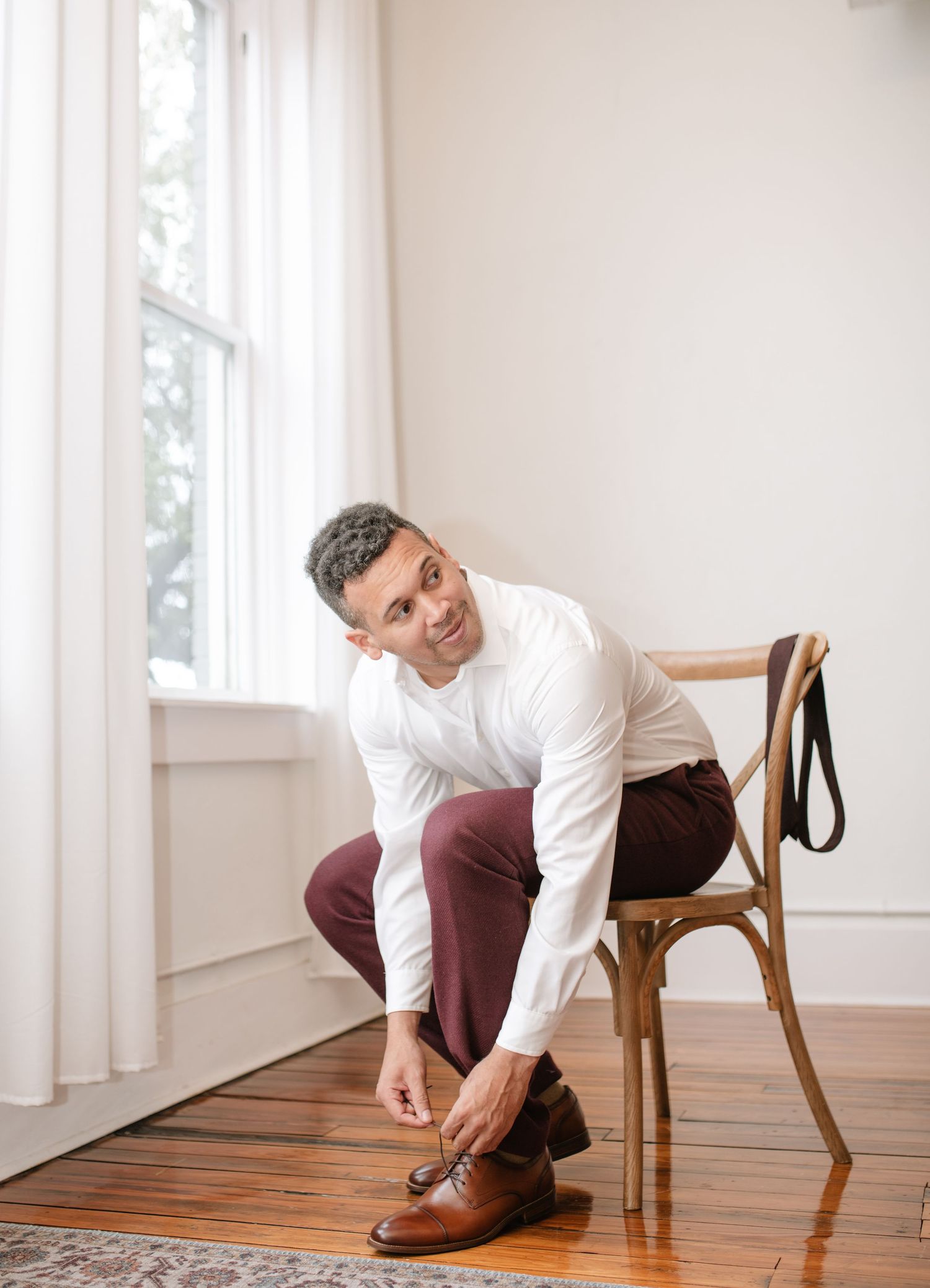 Getting ready scene with brown leather shoes being put on in sunlit room with wooden floors.