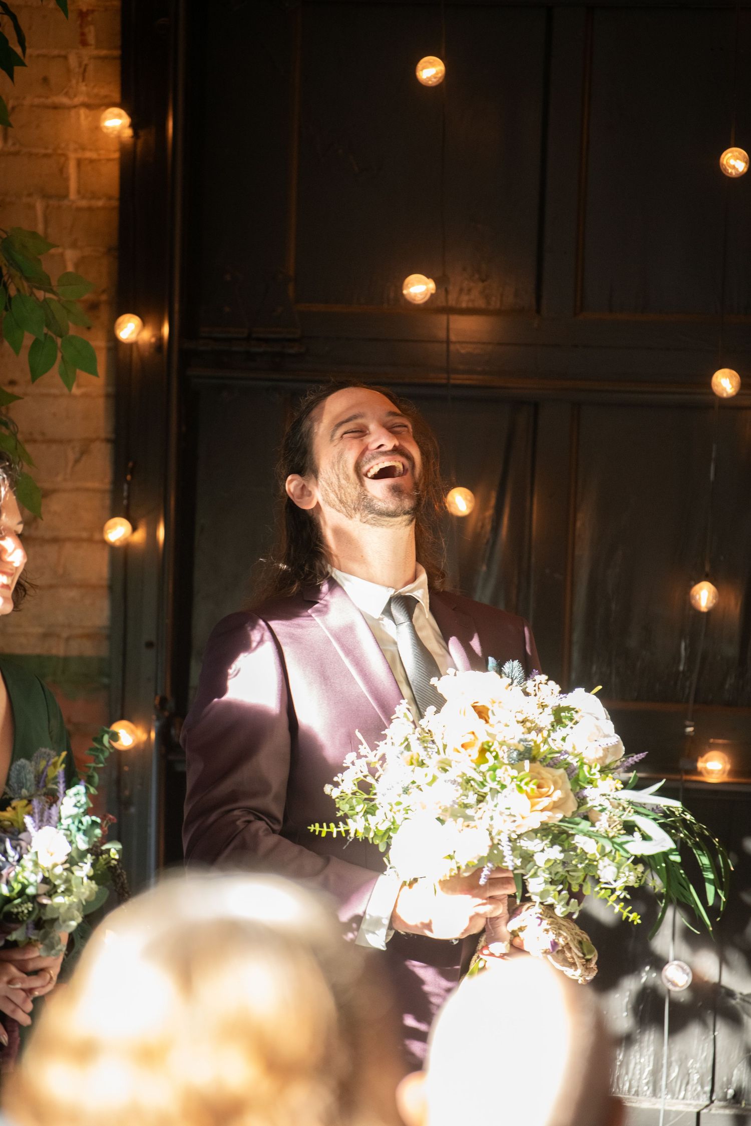 Joyful candid moments captured during wedding speeches under ambient lighting.