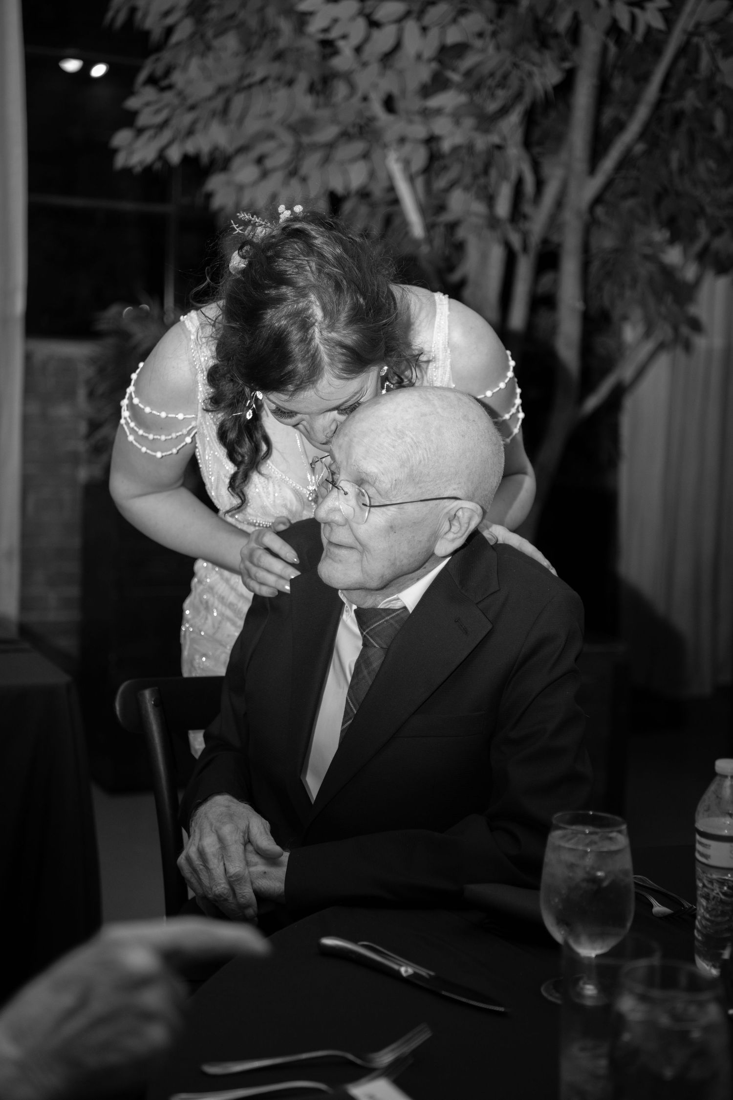 Black and white photo of guests sharing an intimate moment at a wedding reception.