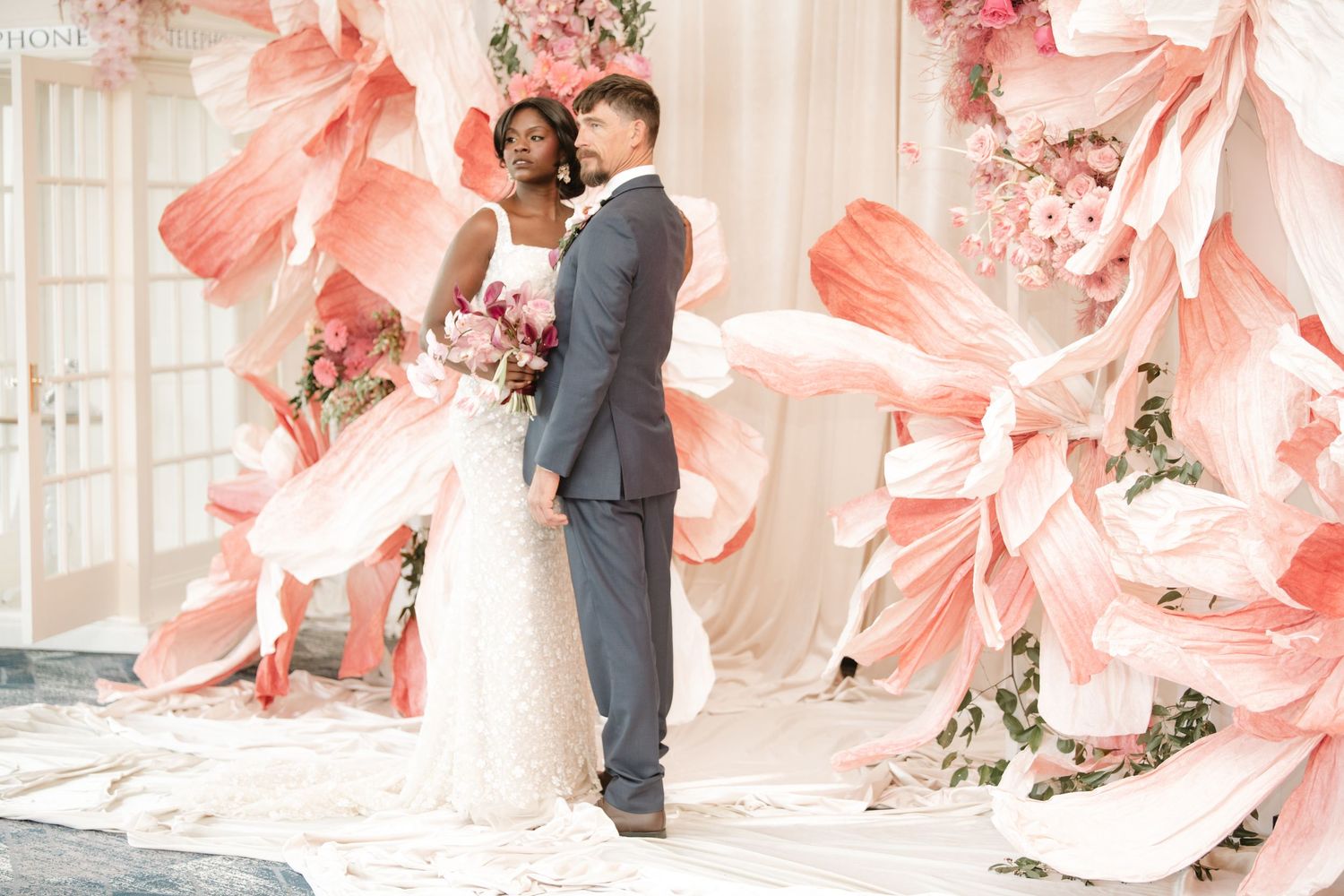 Romantic wedding portraits with oversized coral floral installations and soft lighting.