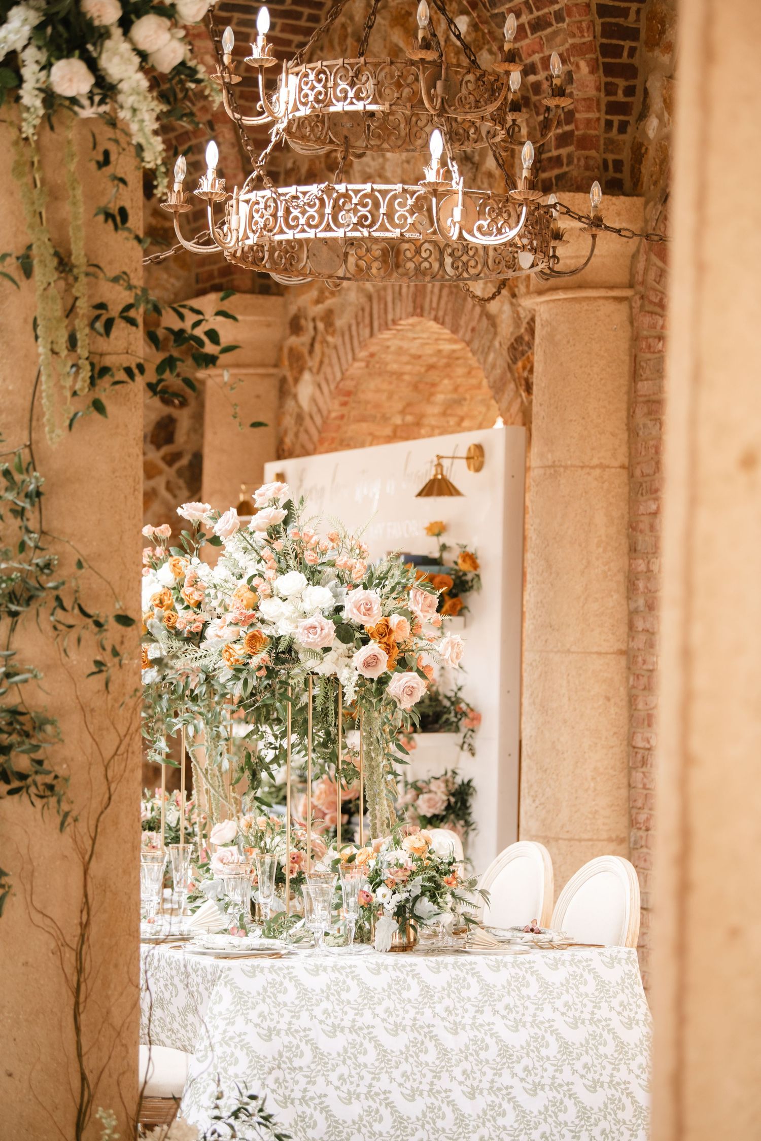 Stone archway venue decorated with hanging chandeliers and floral centerpieces for a romantic wedding reception.