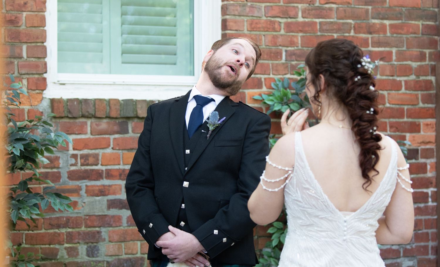 A wedding moment captured against a brick wall with natural lighting.