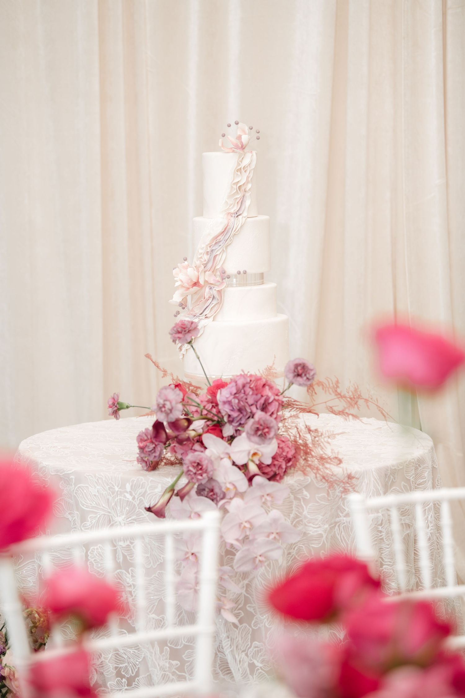 White chiavari chairs with pink floral arrangements at a wedding reception.