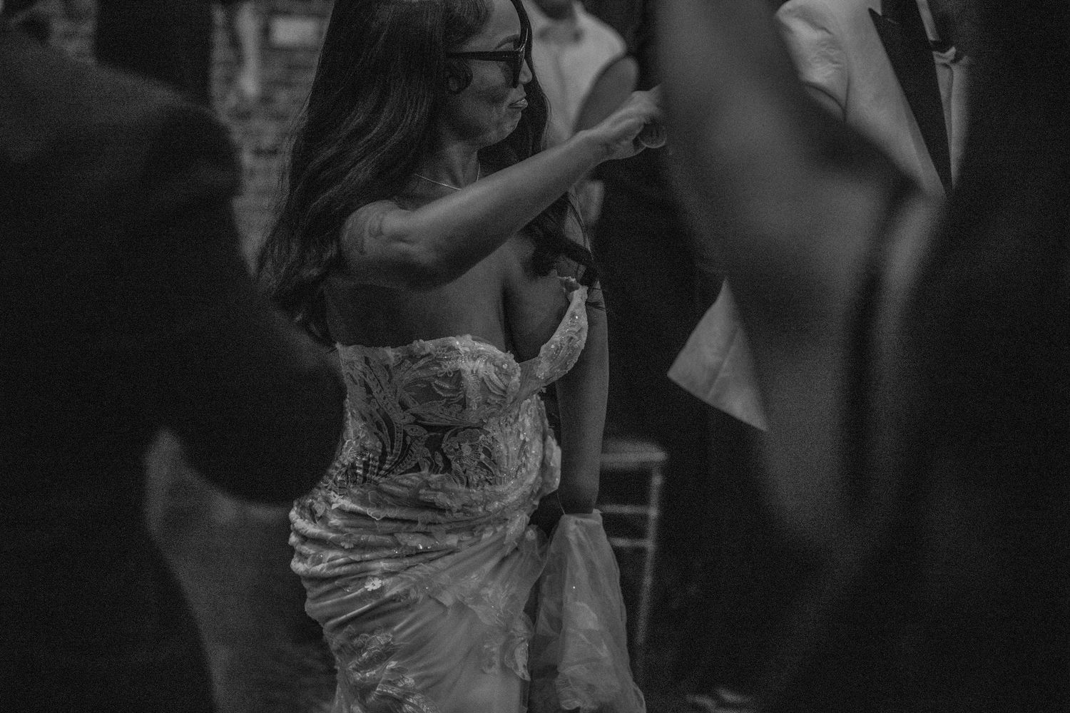 Wedding guests dancing and celebrating at an indoor reception with brick walls.