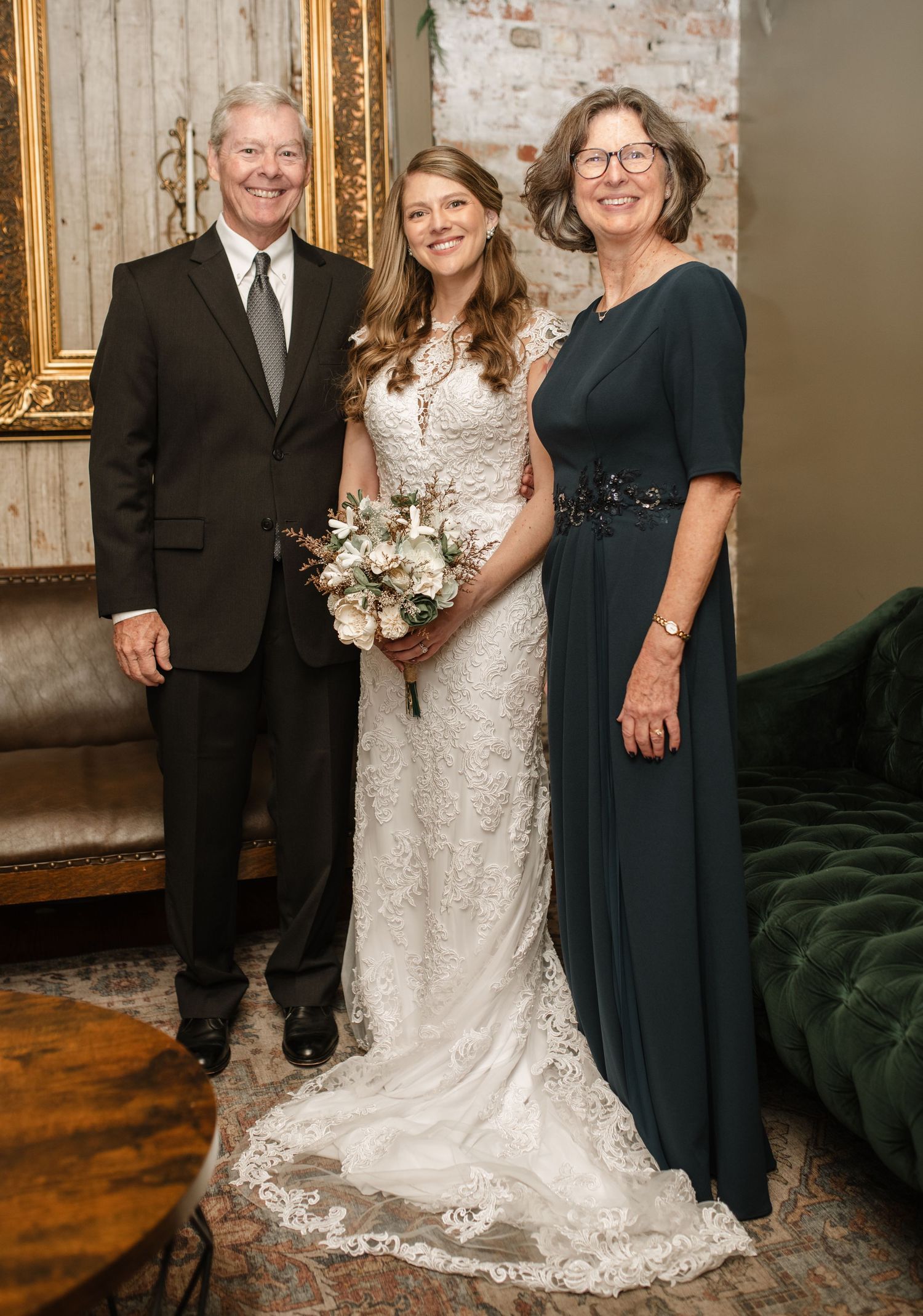 Family formal portraits taken against exposed brick wall at wedding venue.