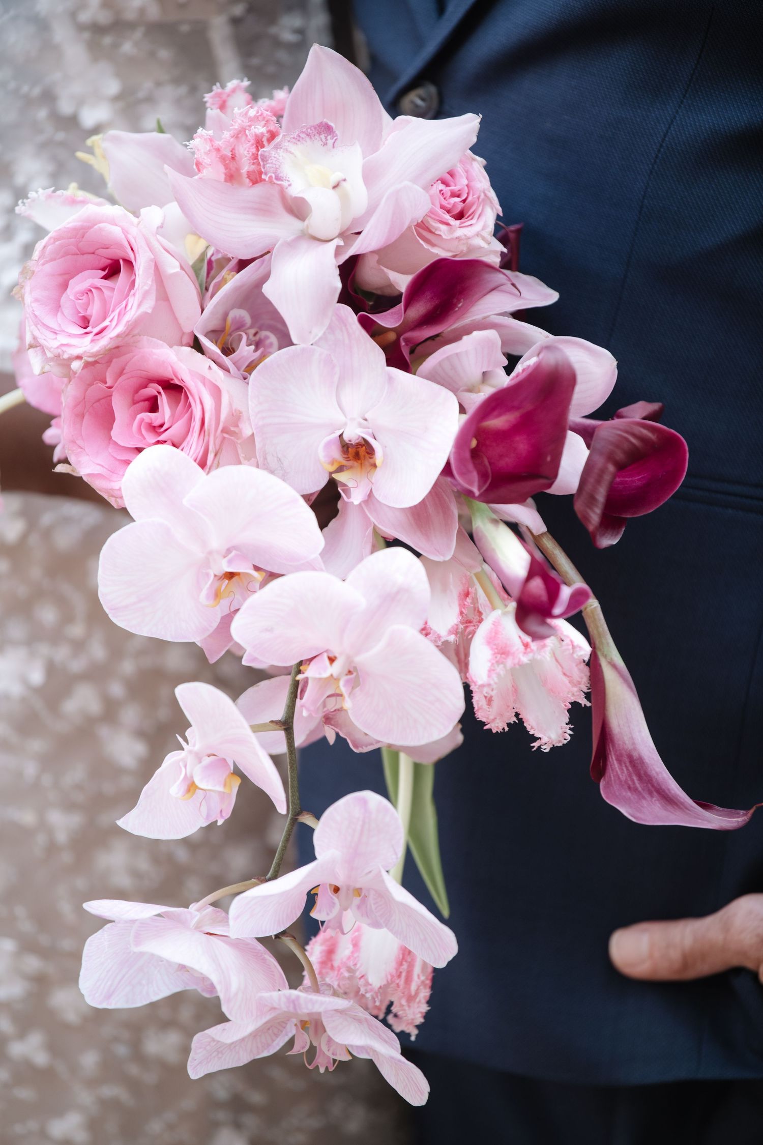 Delicate pink orchid bouquet against navy blue background.