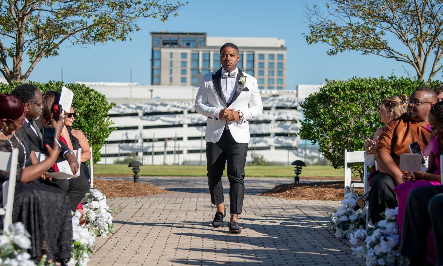 Outdoor wedding venue setup with chairs and decorations against urban backdrop.