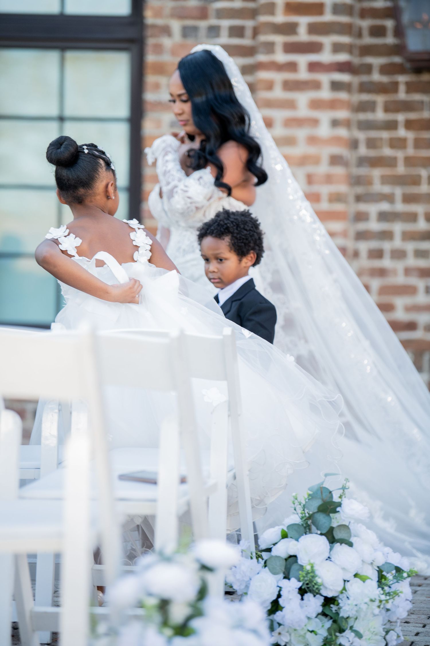 White floral arrangements and decor line an elegant outdoor wedding ceremony space.