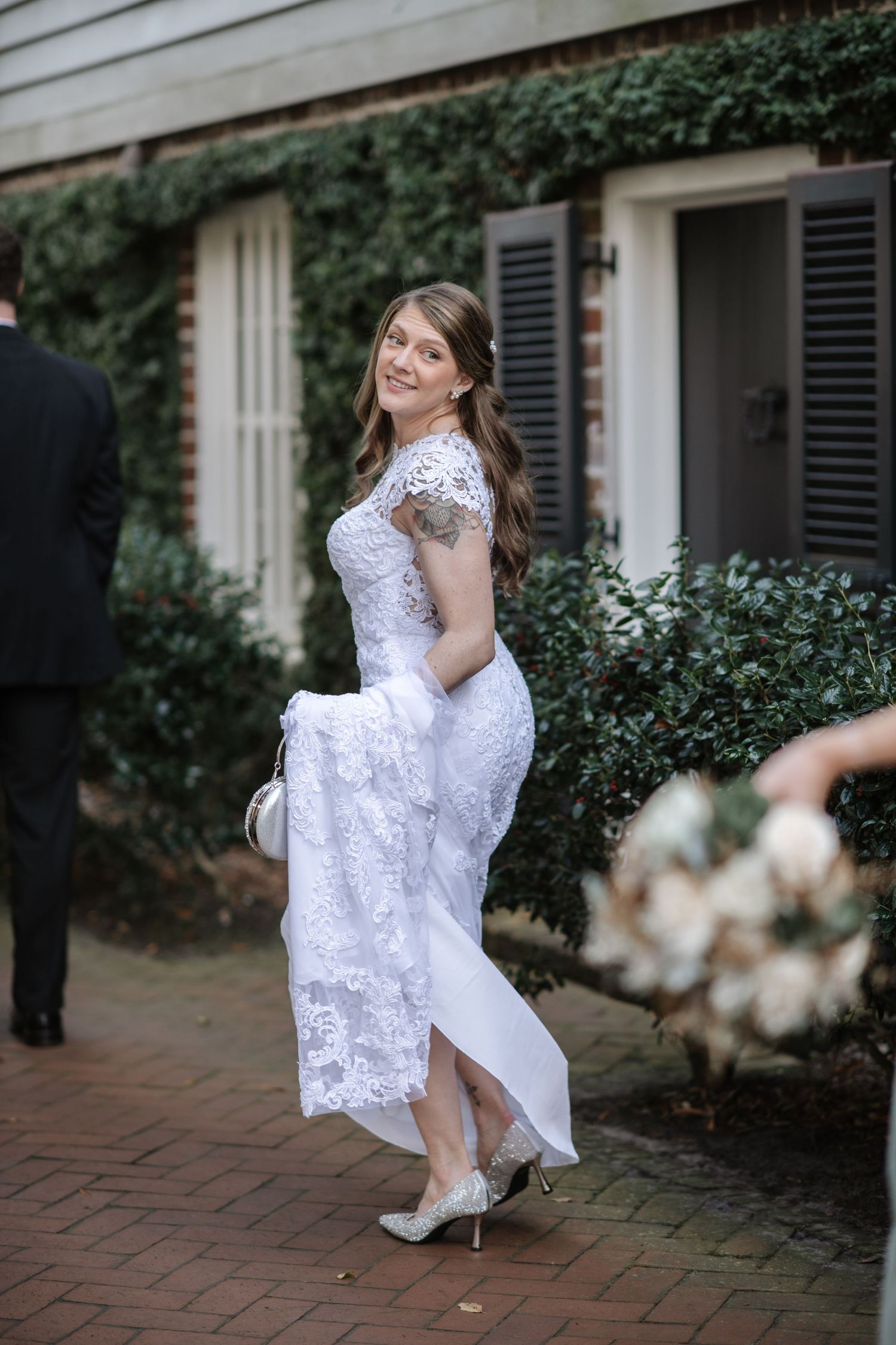 A playful portrait on a brick pathway with ivy-covered walls in the background.