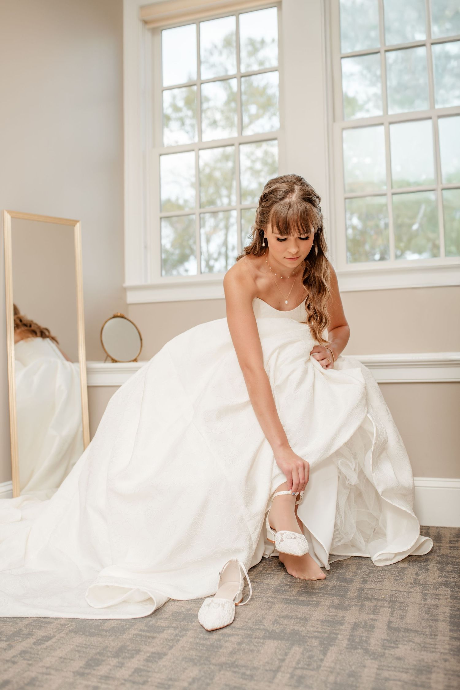 A series of photos showing a bride in a white gown adjusting her shoes in a bright sunlit room.