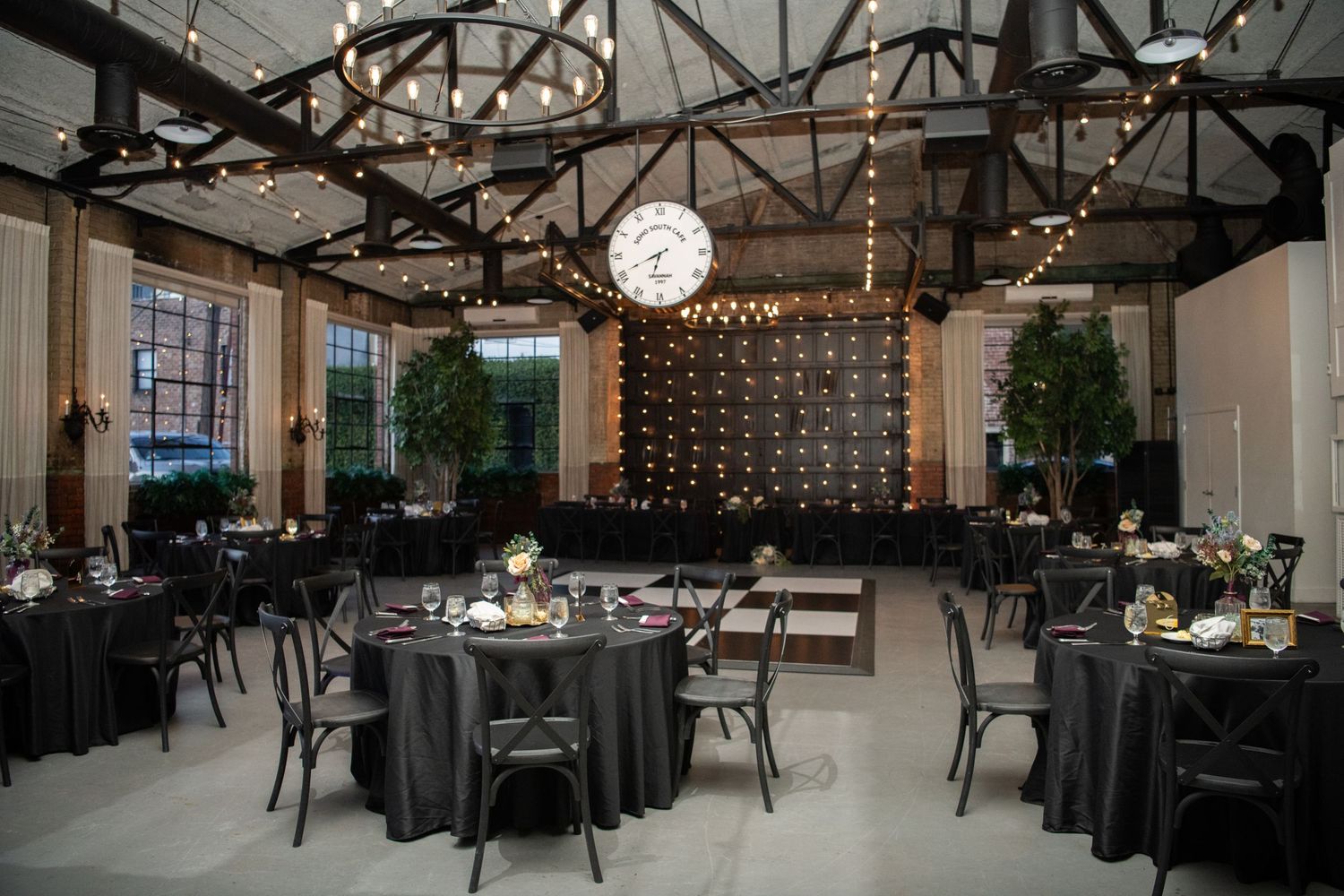 Wedding reception venue with exposed brick walls and string lights creating an intimate industrial atmosphere.