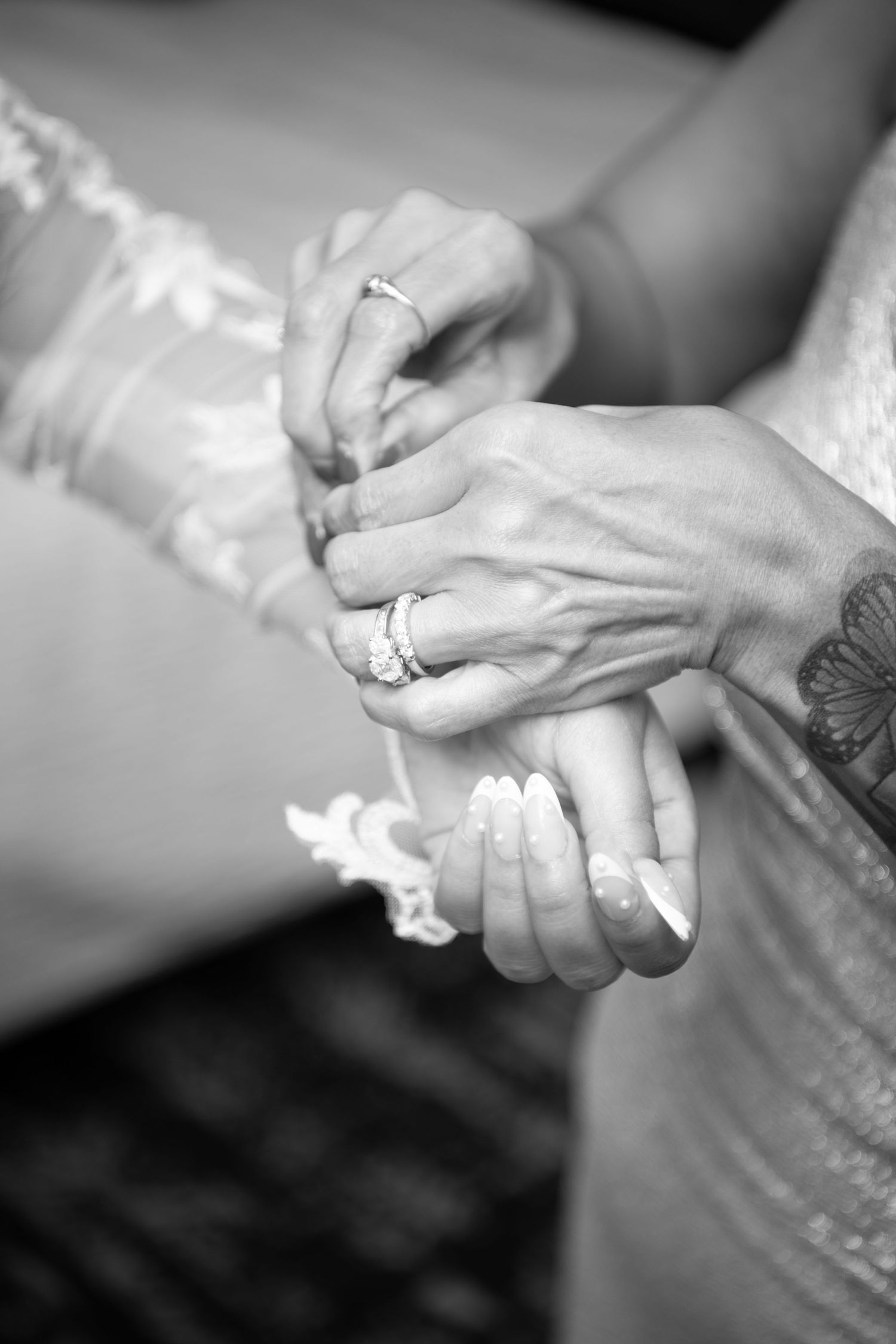 Close-up black and white shot of hands exchanging rings during a wedding ceremony.