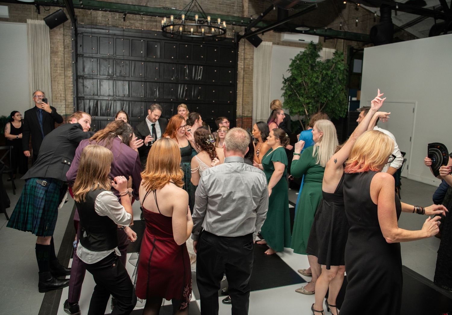 Wedding reception dance floor filled with guests in formal wear and kilts.