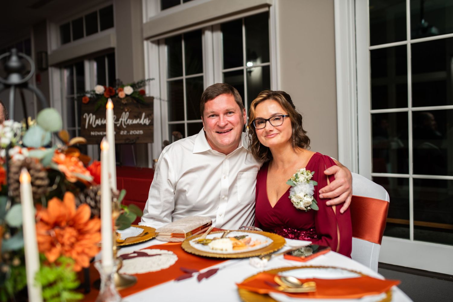 Guests enjoying dinner at an elegant reception with white tablecloths and window views.