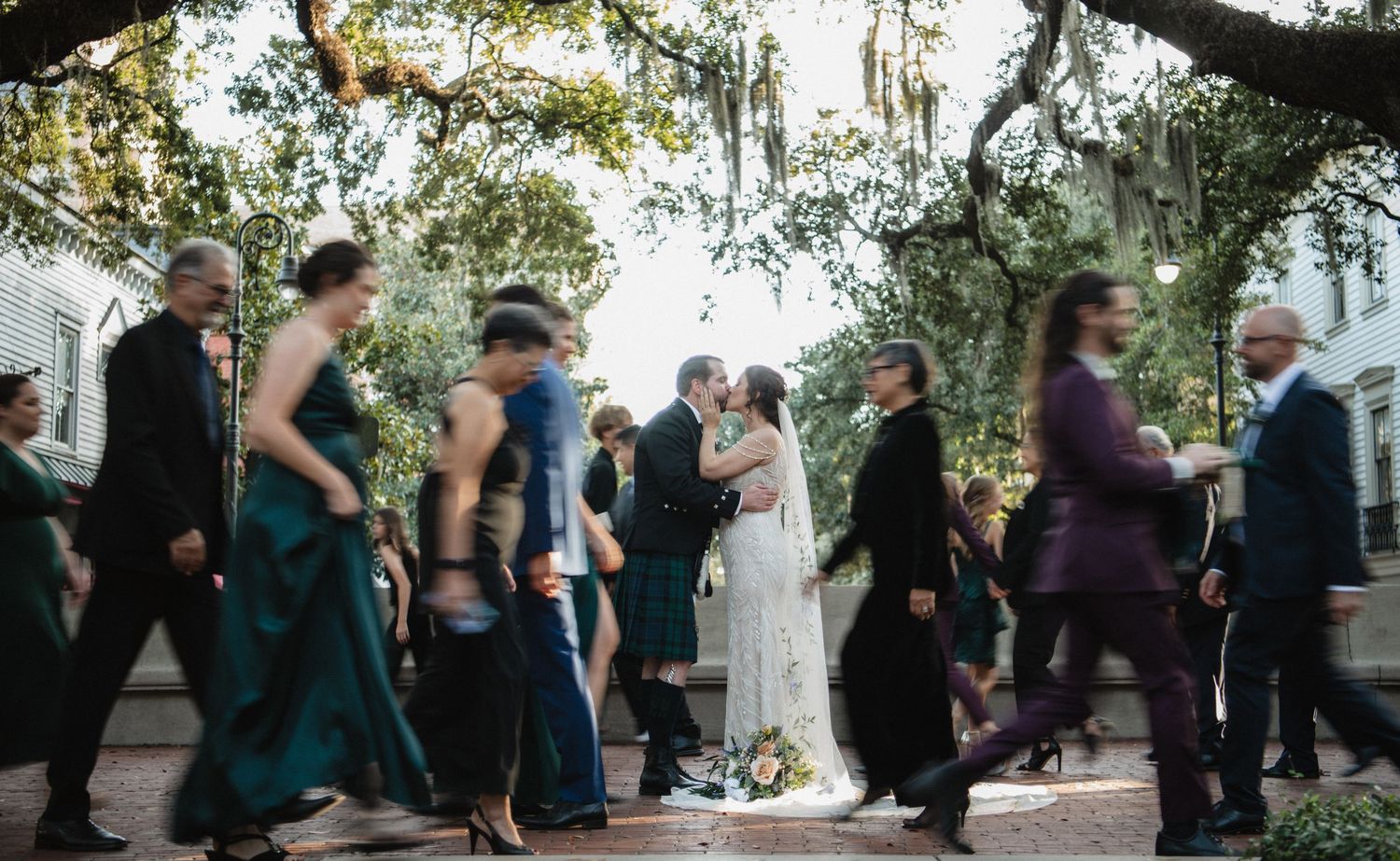 Guests dancing in motion blur under tree branches at an outdoor celebration.