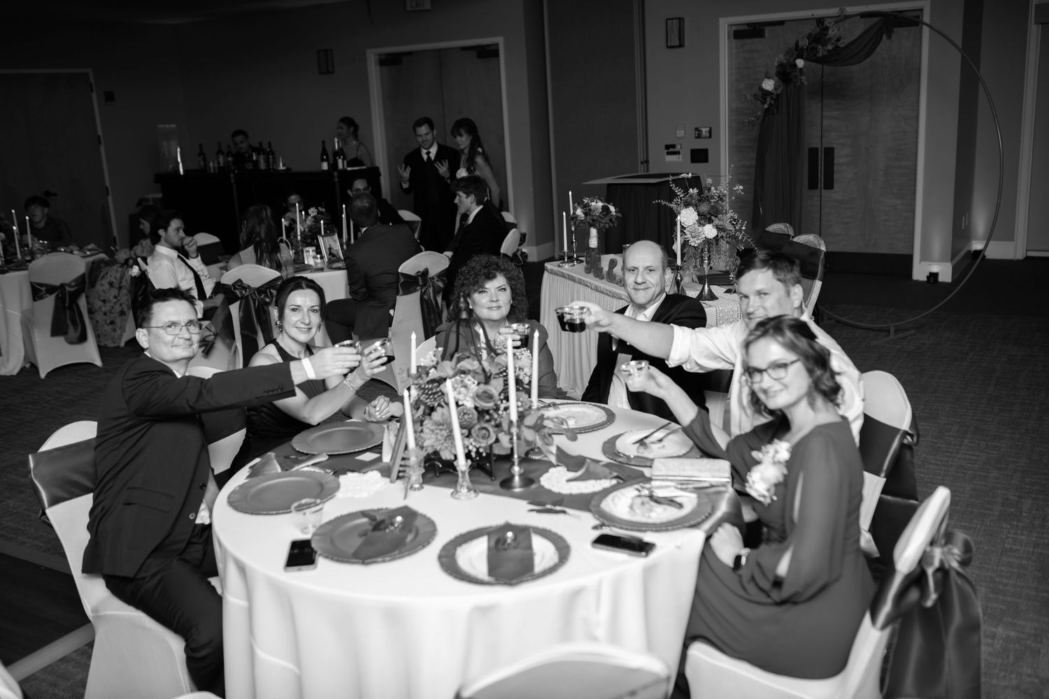 Wedding reception guests seated at elegantly decorated round tables with white linens and centerpieces.