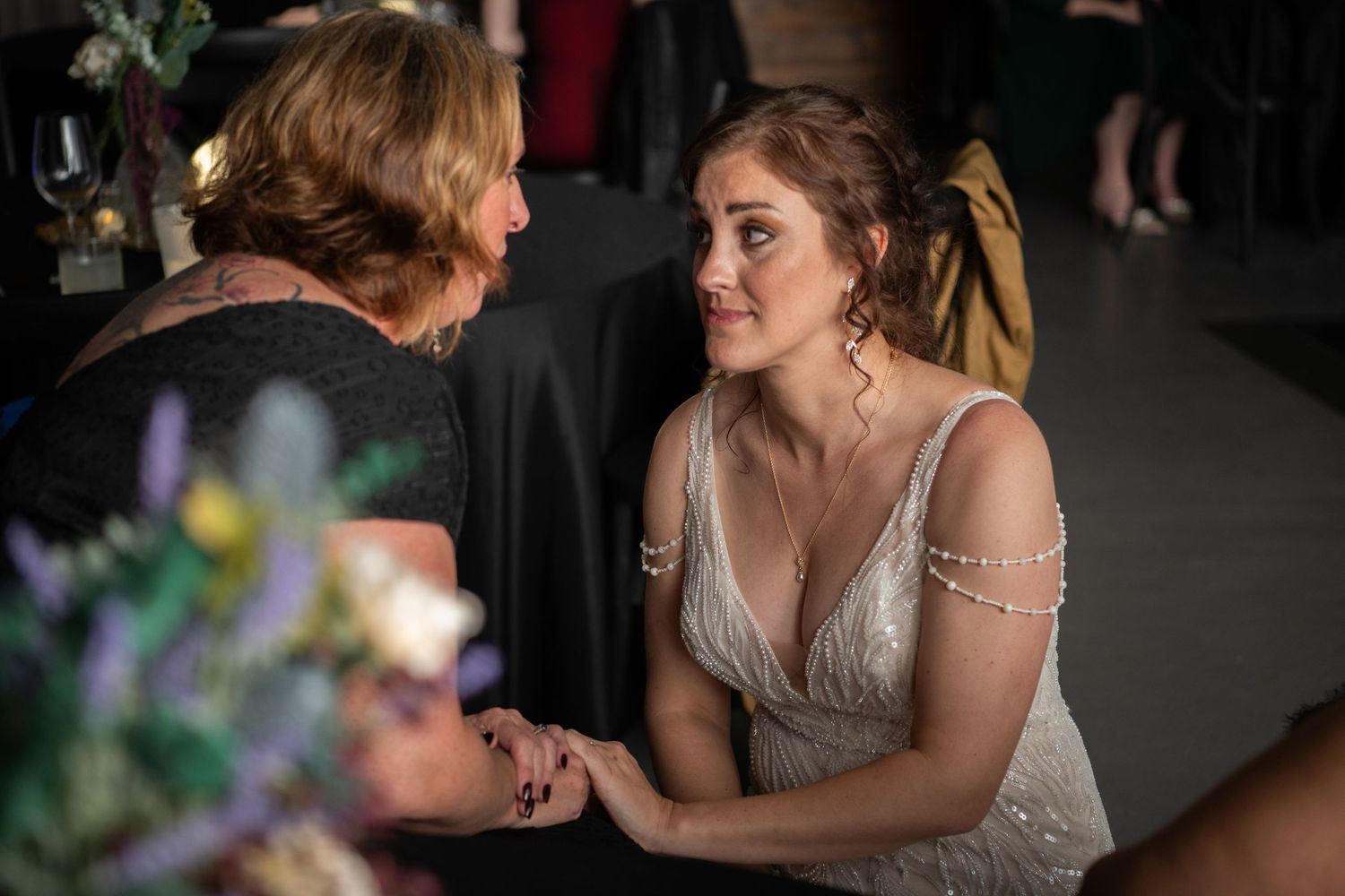 Intimate moment between bride and guest during wedding reception.