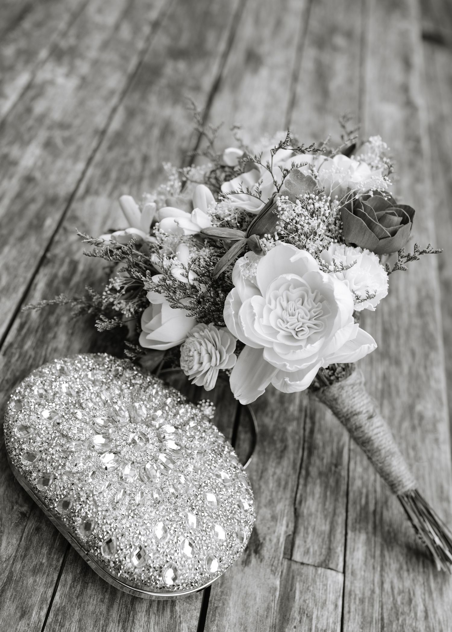 Black and white photo of elegant floral arrangements with roses and crystals on wooden surface.