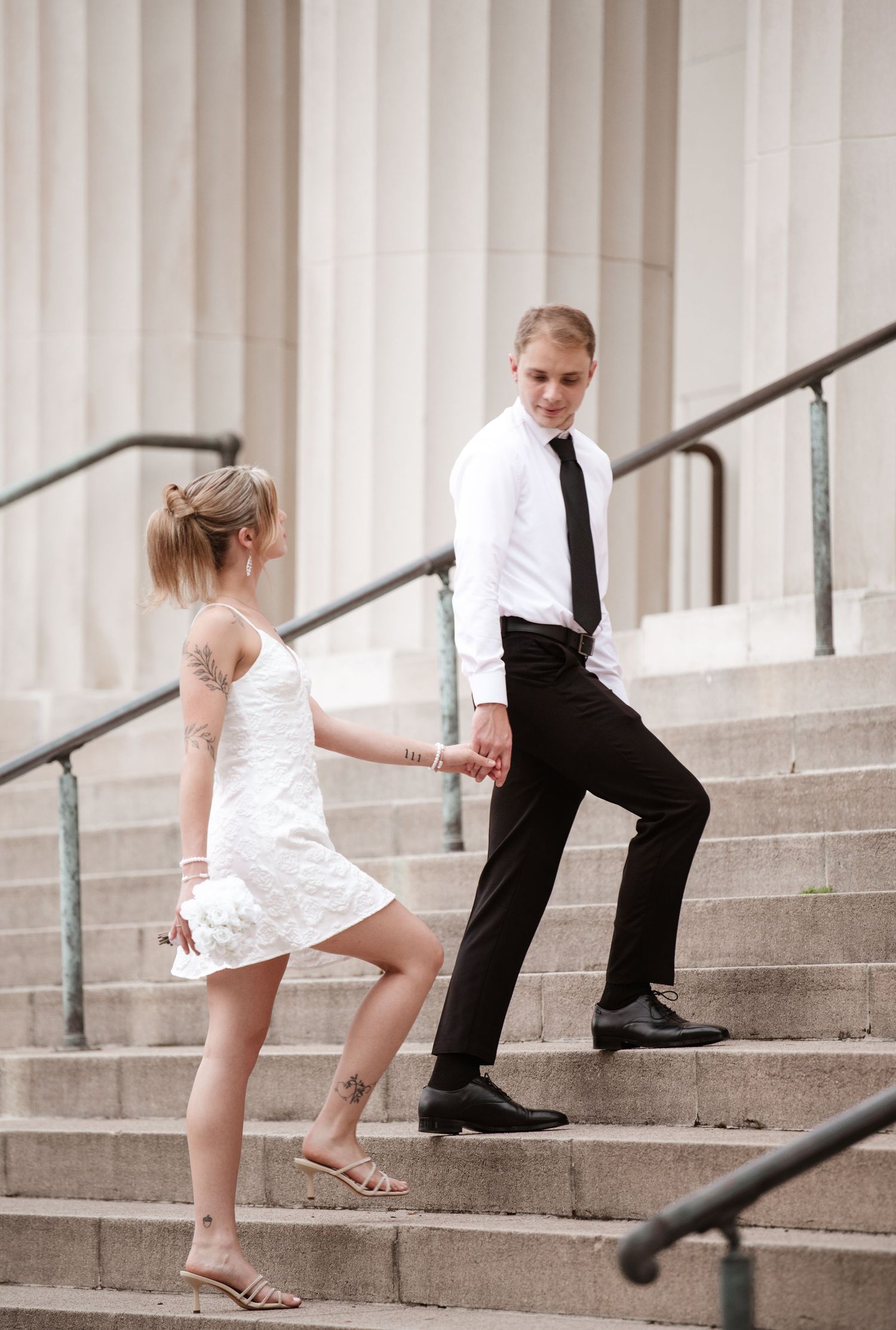 Playful sequence on grand stone steps with white columns in background.