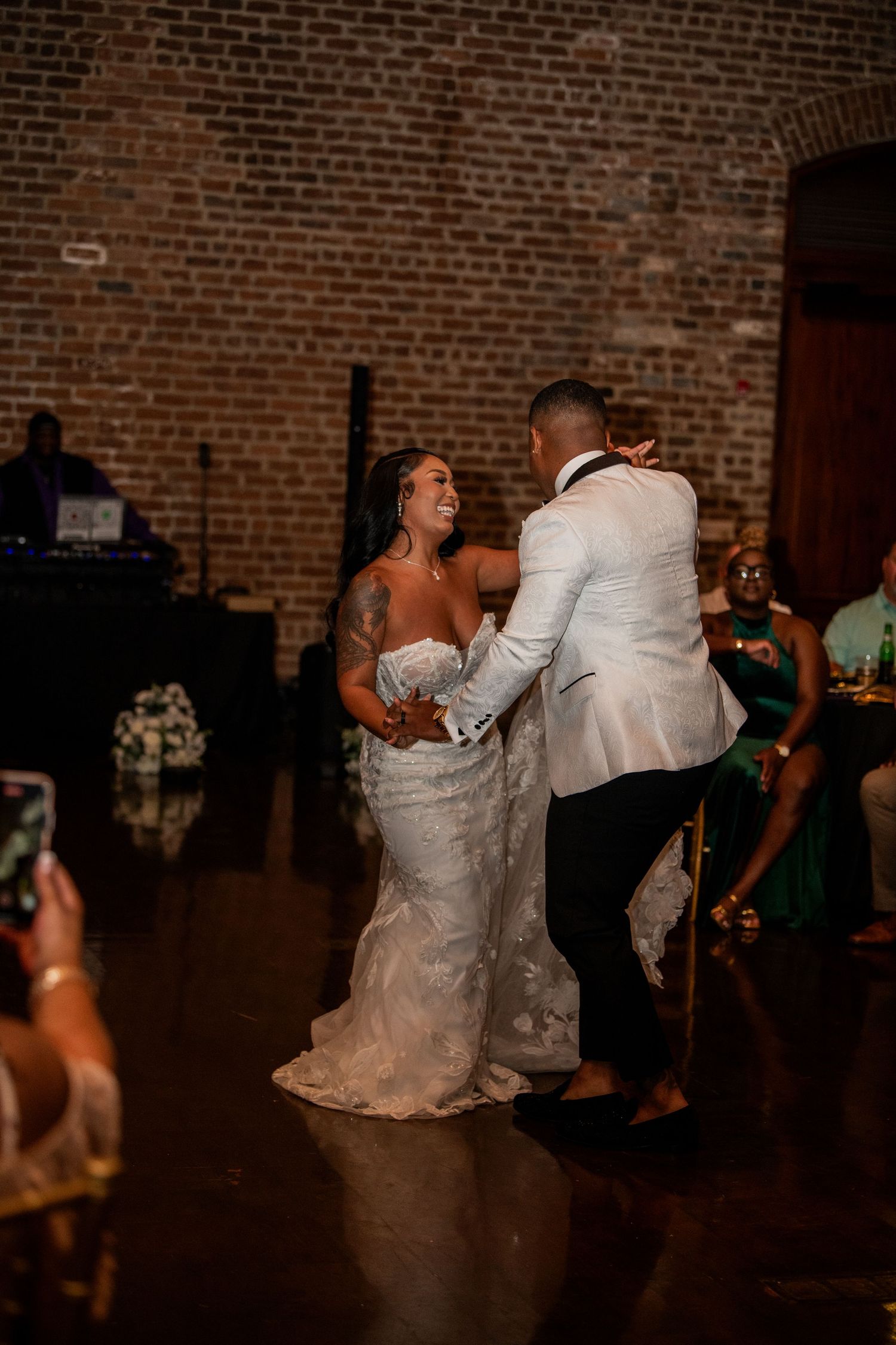 Newlyweds dancing together in an elegant brick venue with romantic lighting.