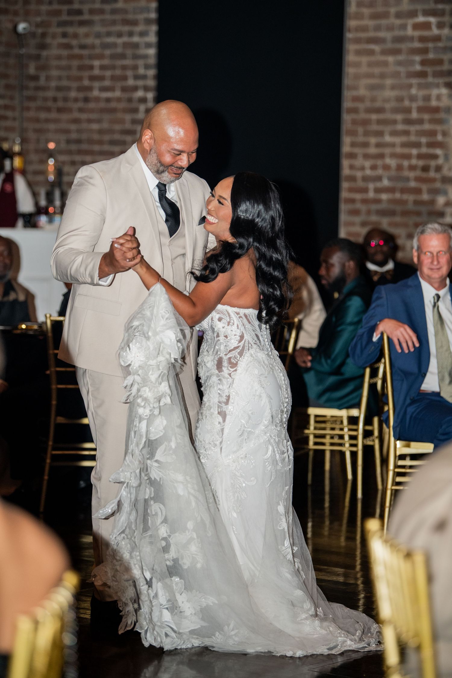 Romantic wedding dance moment in a rustic venue with exposed brick walls.
