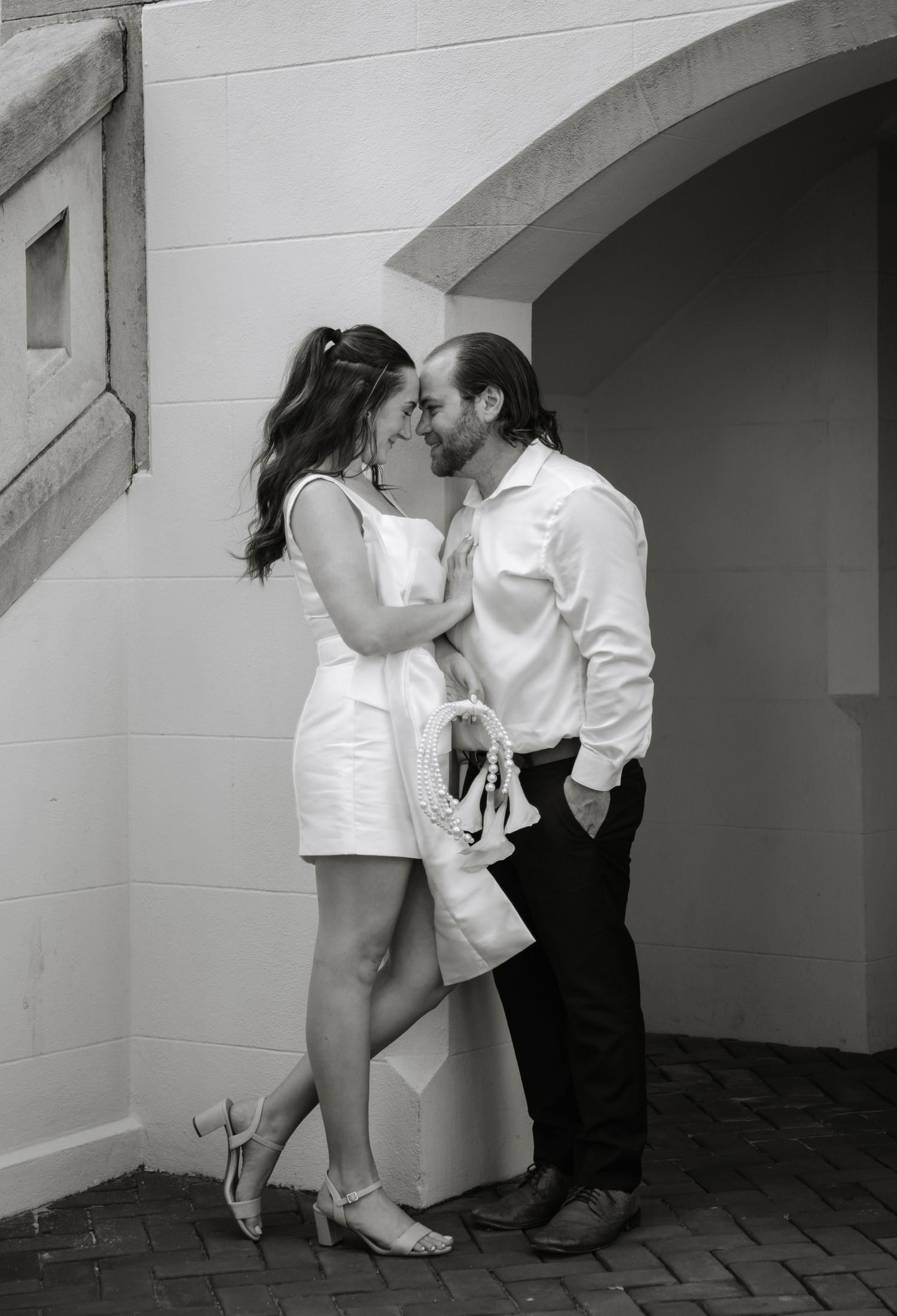 A romantic black and white photograph of a couple sharing an intimate moment under an arched doorway.