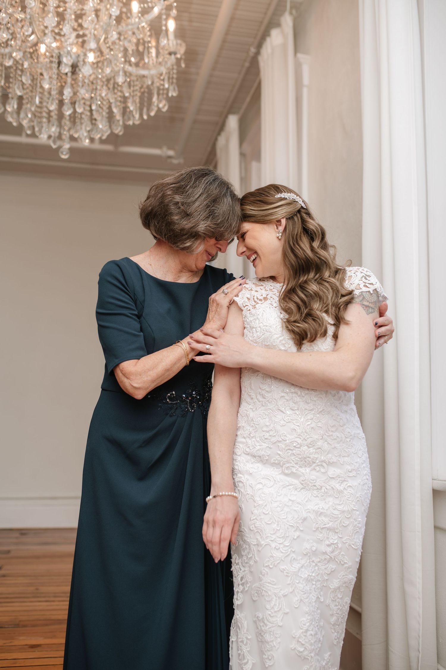 Emotional moment shared in elegant room with chandelier and hardwood floors.