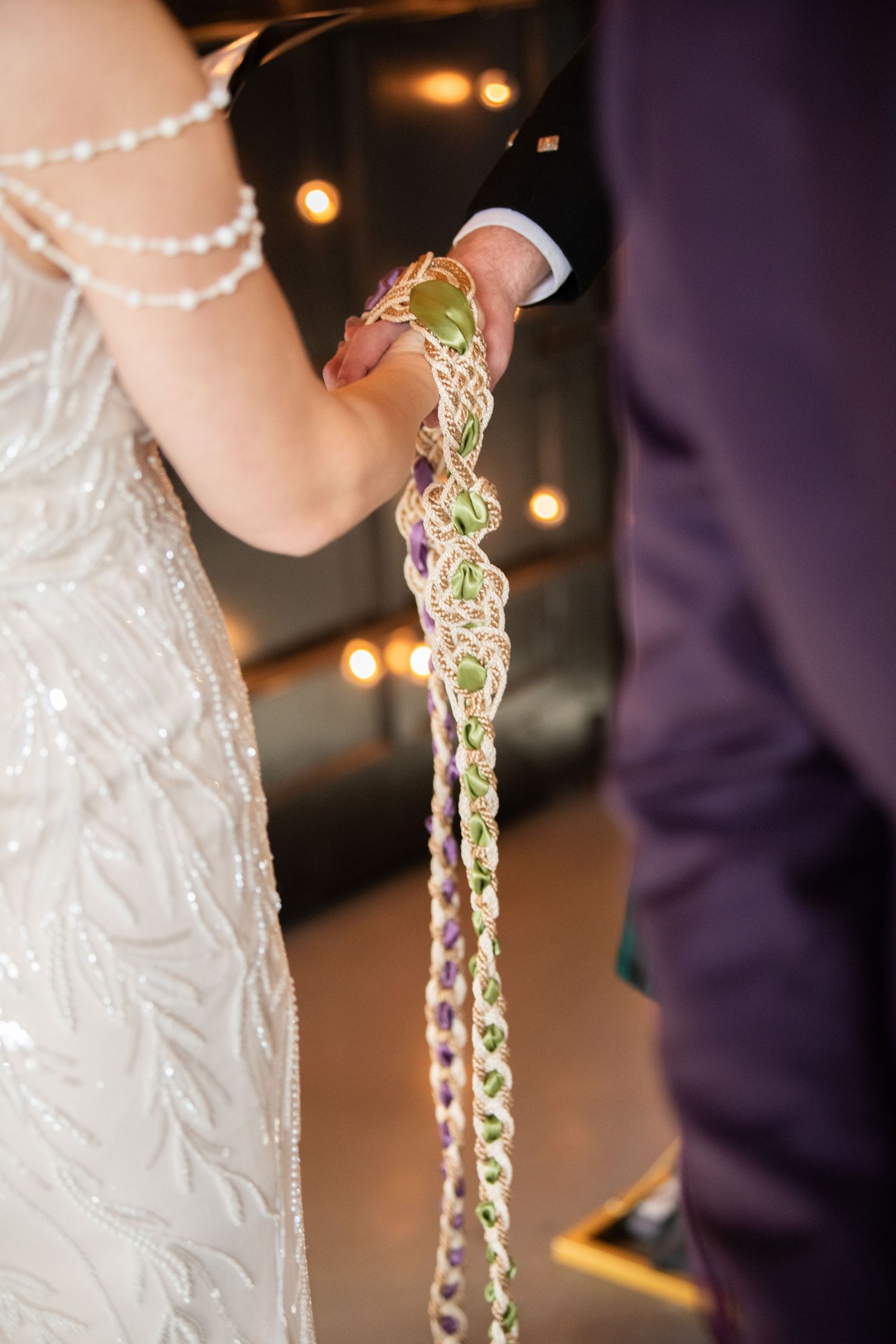 Close-up of decorative braided cord being held during a wedding ceremony.