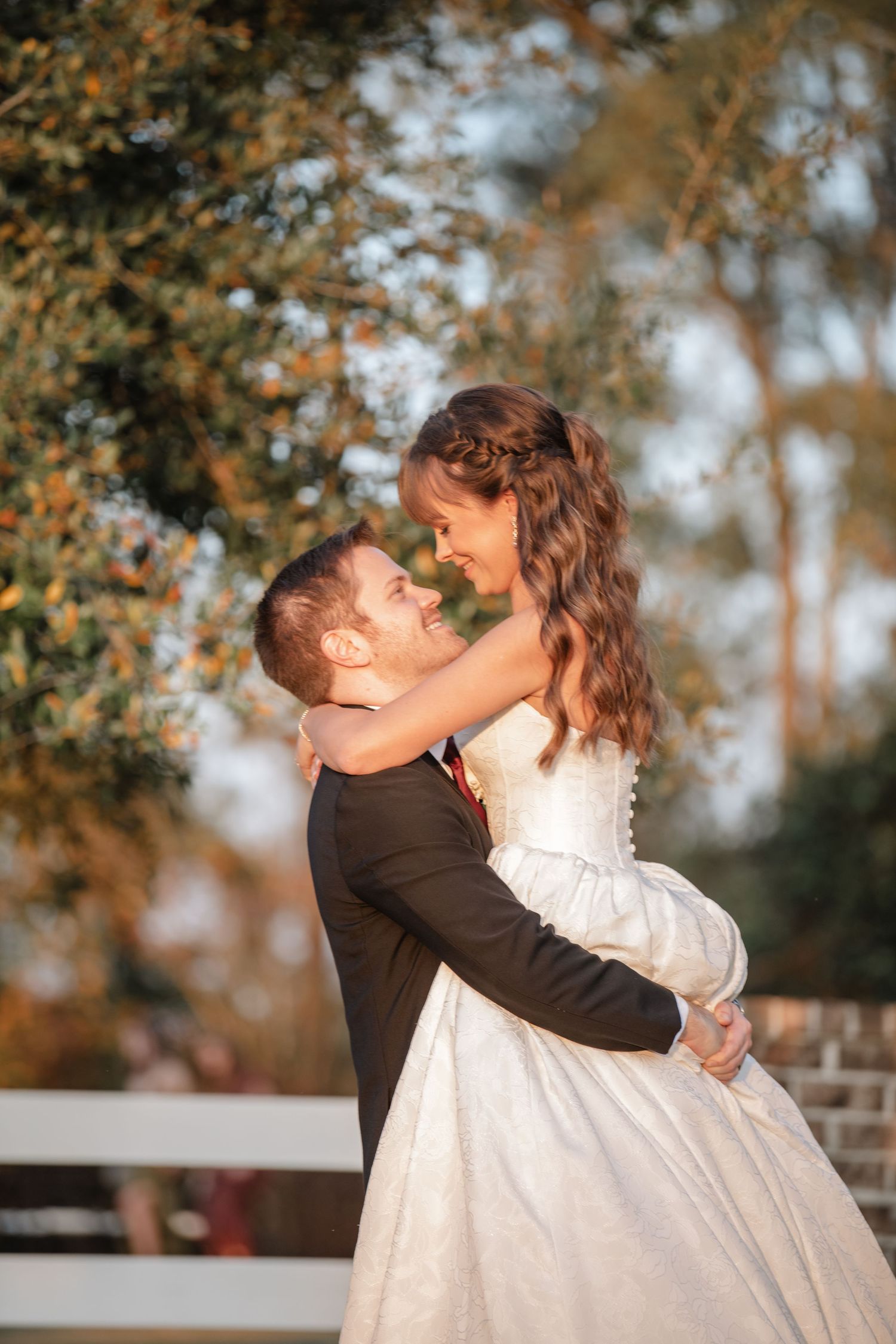 A romantic sunset moment as the groom lifts the bride in her flowing white gown.
