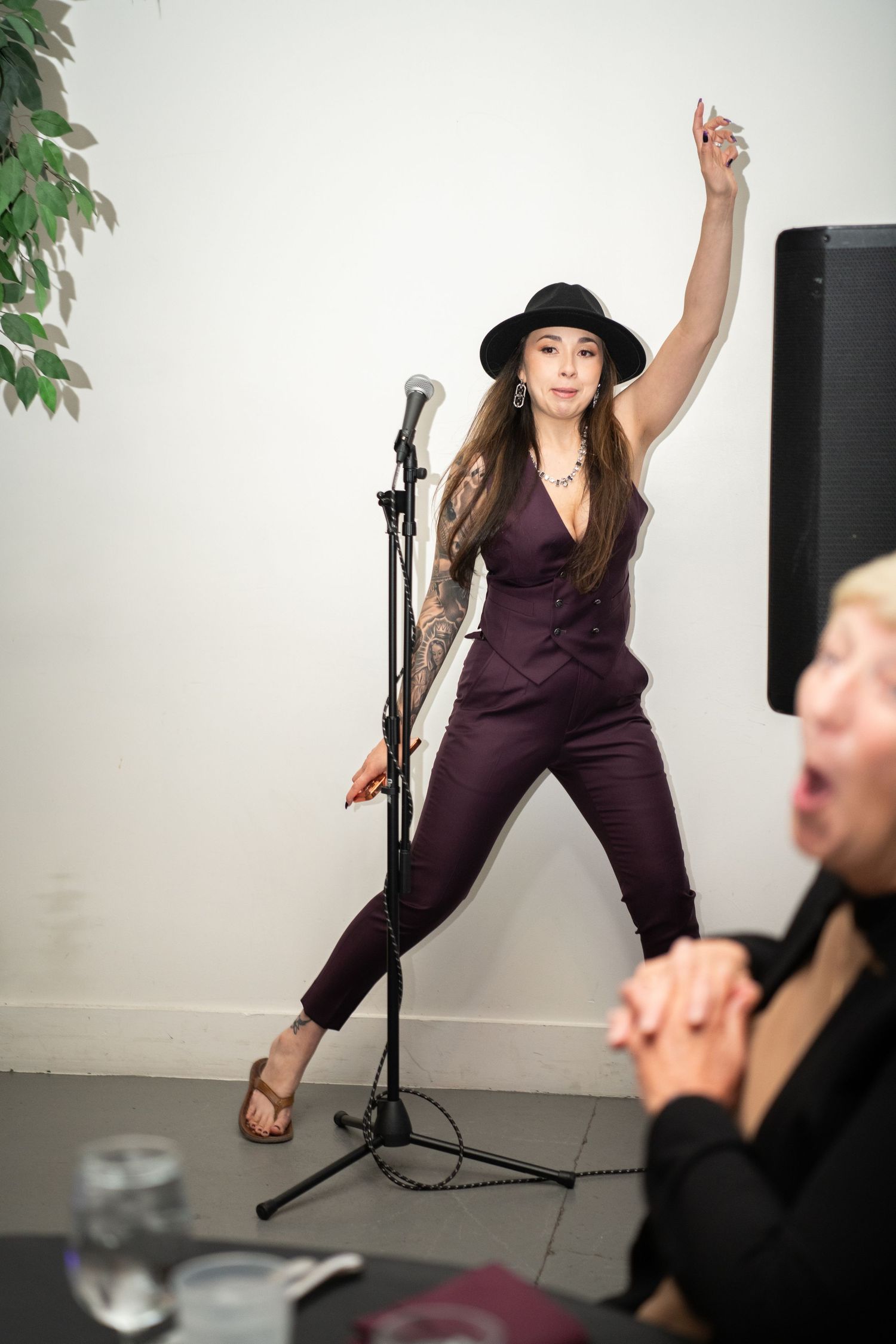Performer in a black hat and purple outfit dancing energetically in a studio setting.
