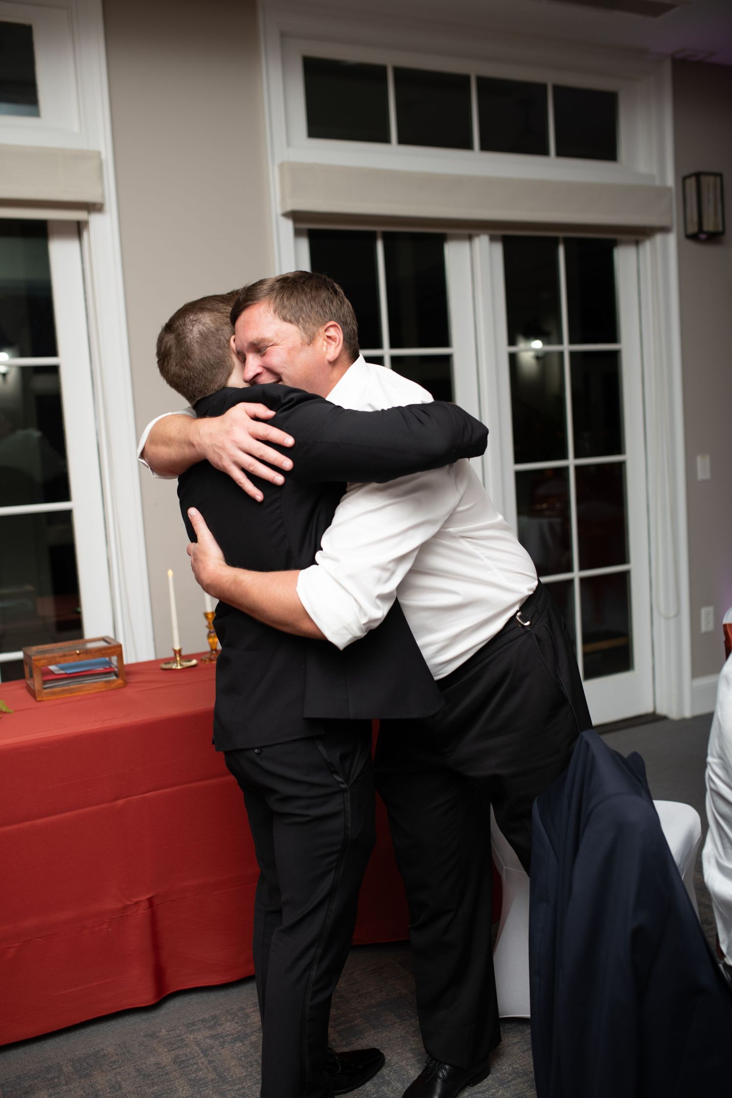 Two people sharing an emotional embrace at an indoor event.