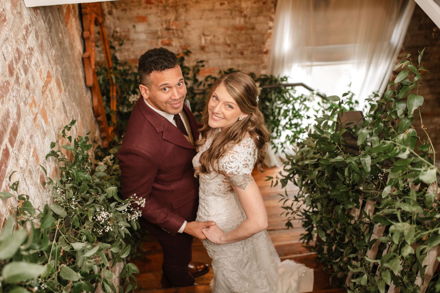 A romantic wedding photoshoot in a rustic brick-walled venue with elegant decor and greenery.