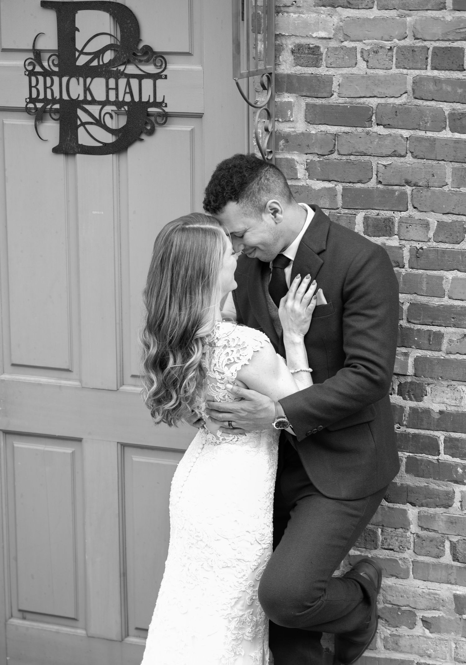 Black and white wedding portraits showing tender moments at a historic brick venue.