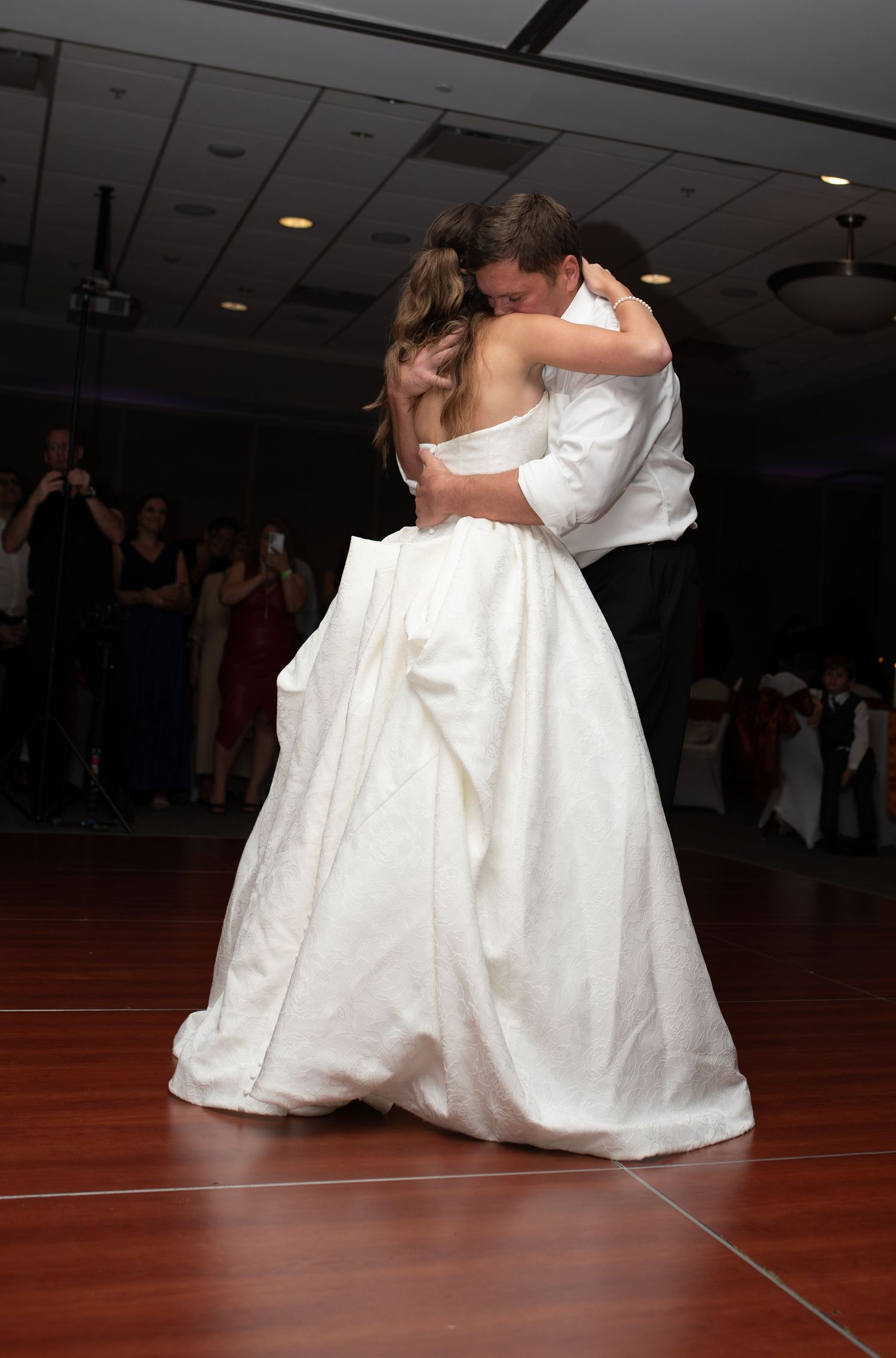 Couple sharing intimate dance moves on wooden floor during wedding reception.