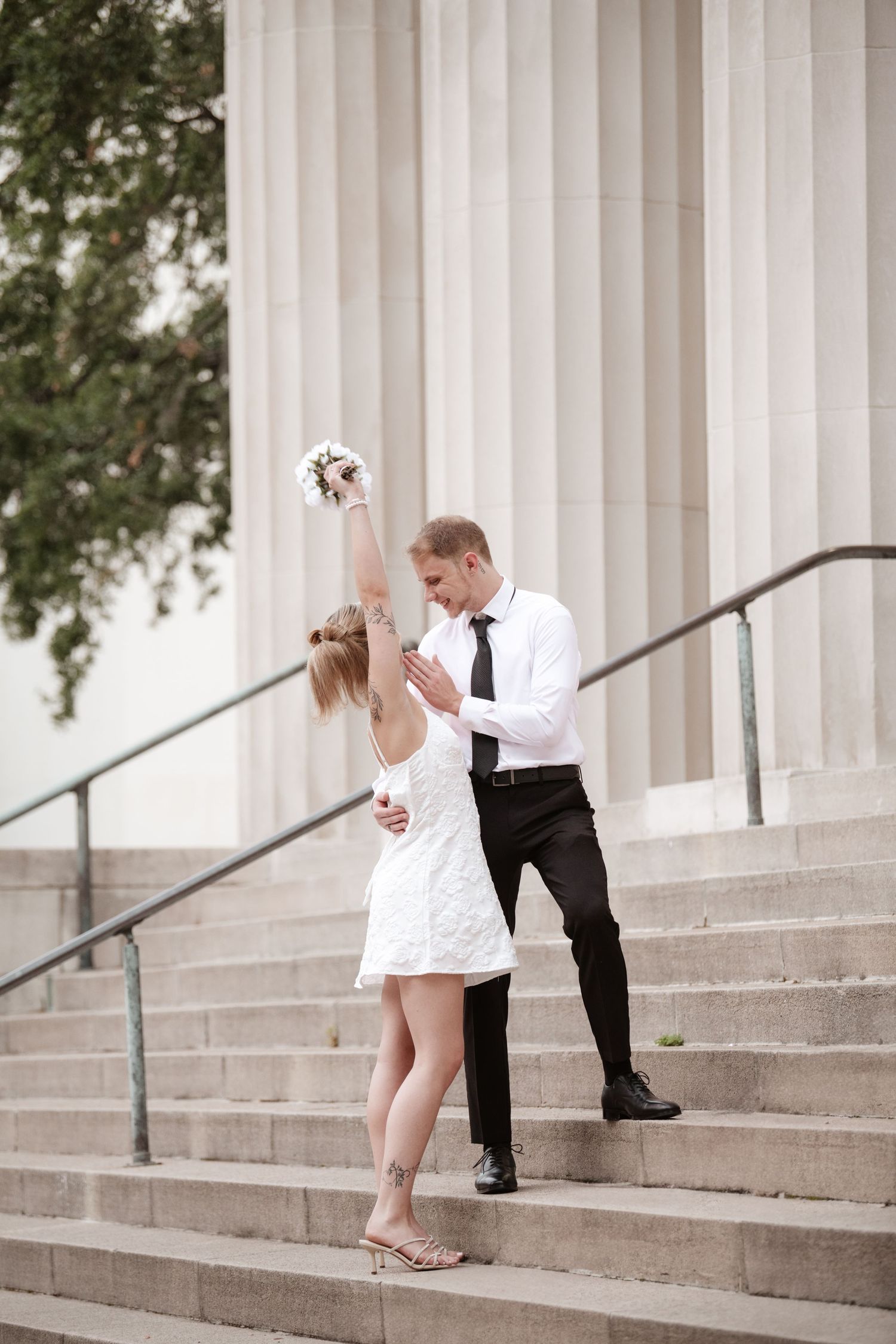 Dancing sequence captured on stone steps of neoclassical building with columns.