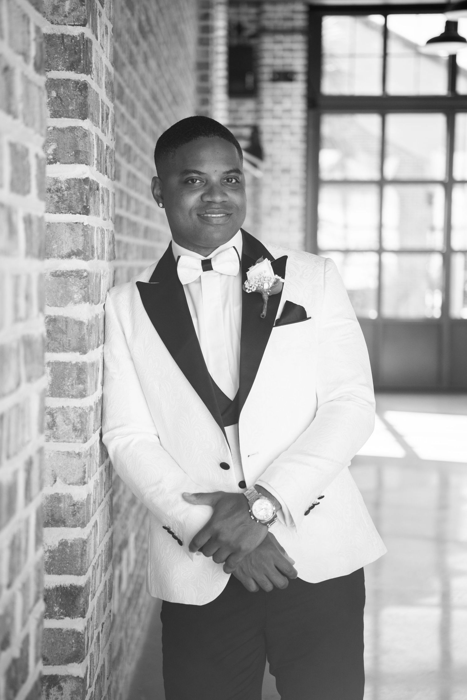 Black and white portraits of groomsmen in white dinner jackets against brick interior.