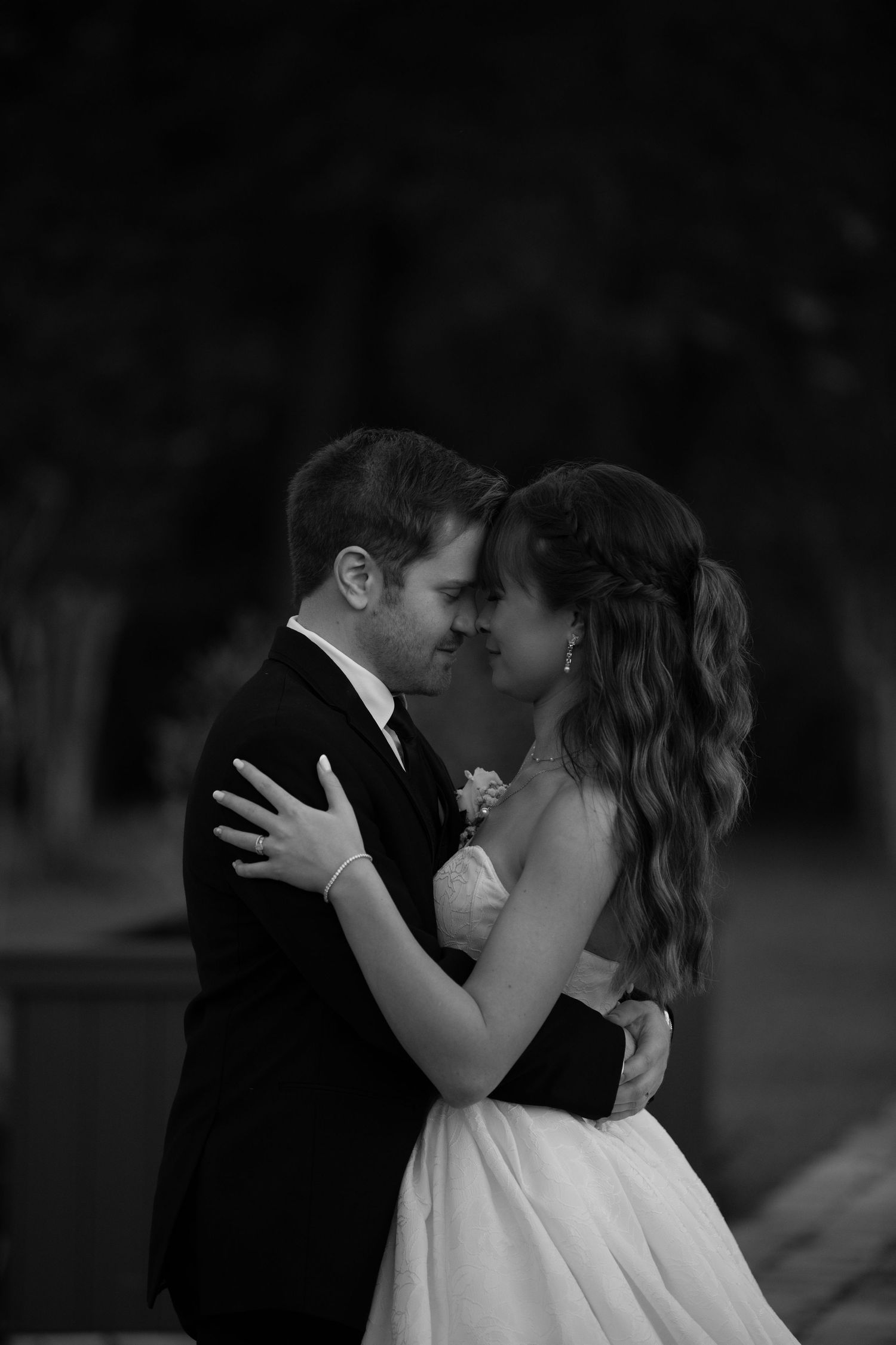 Black and white romantic portrait of a couple in wedding attire sharing an intimate moment.