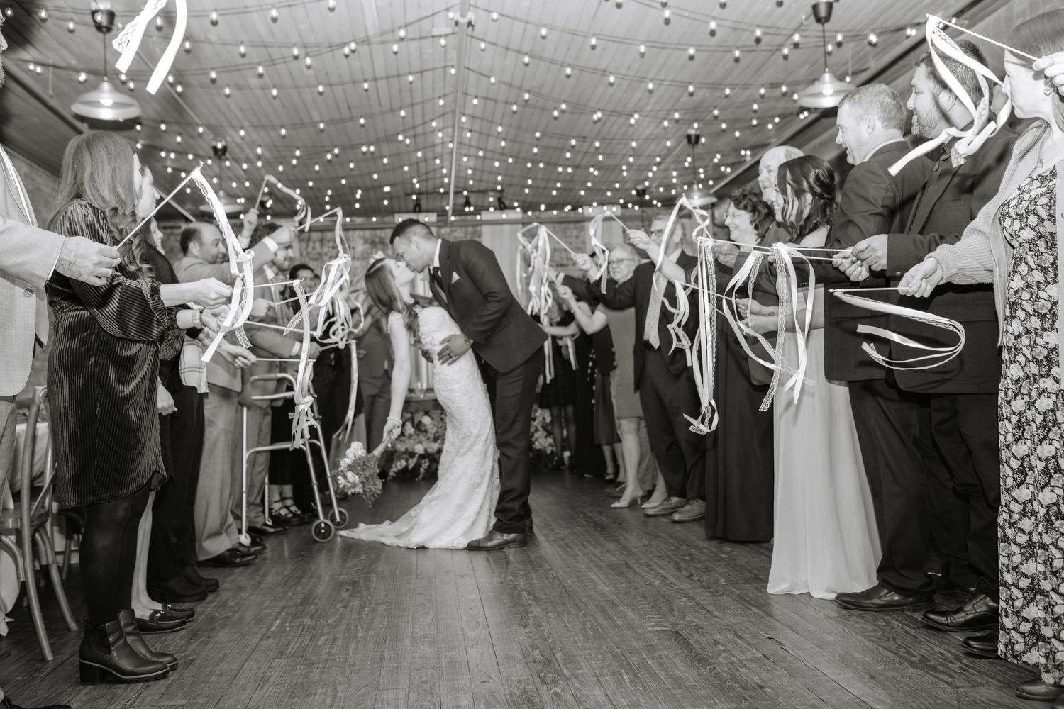 Wedding guests line a pathway holding sparklers during an evening reception celebration.