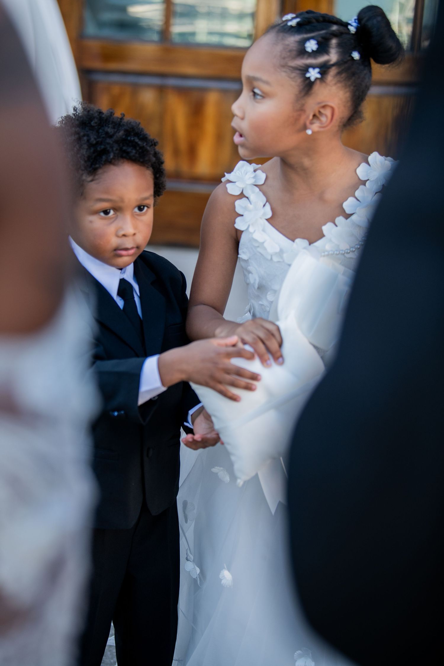 Young attendants in formal wedding attire holding hands during ceremony.
