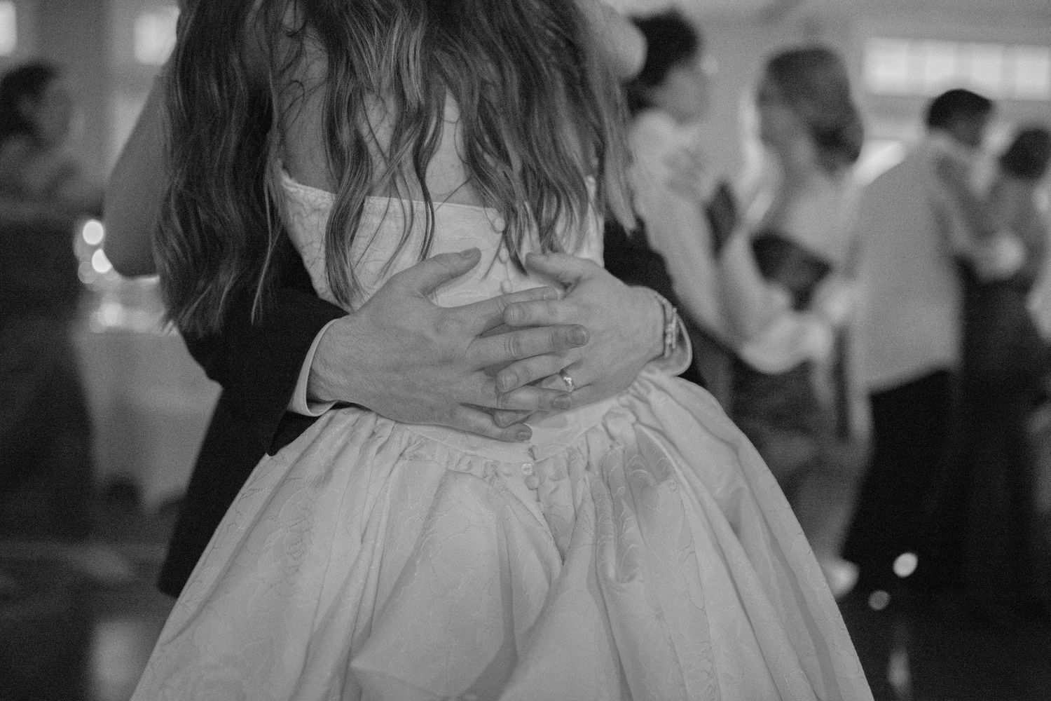 Elegant white wedding dress twirls during a dance in a softly lit reception venue.