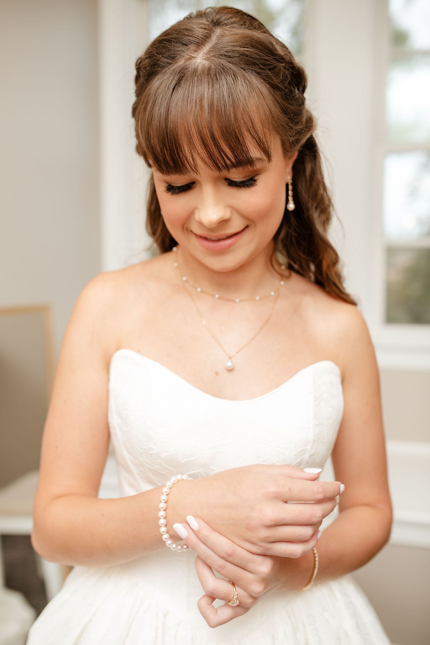 Detail shots of someone adjusting jewelry and accessories while wearing a strapless white wedding gown.