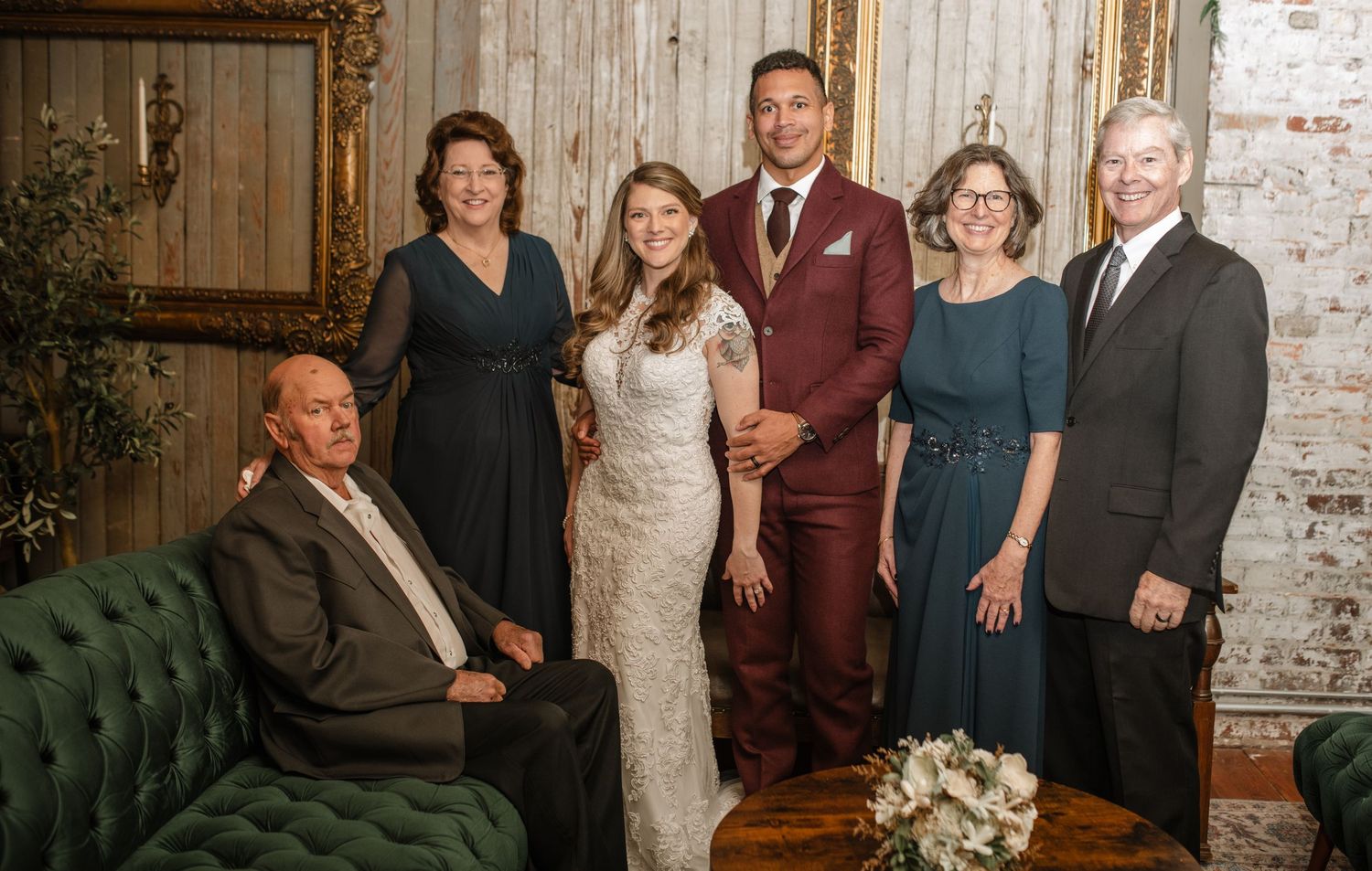 Wedding party poses for formal group photos in an industrial-chic venue with brick walls.
