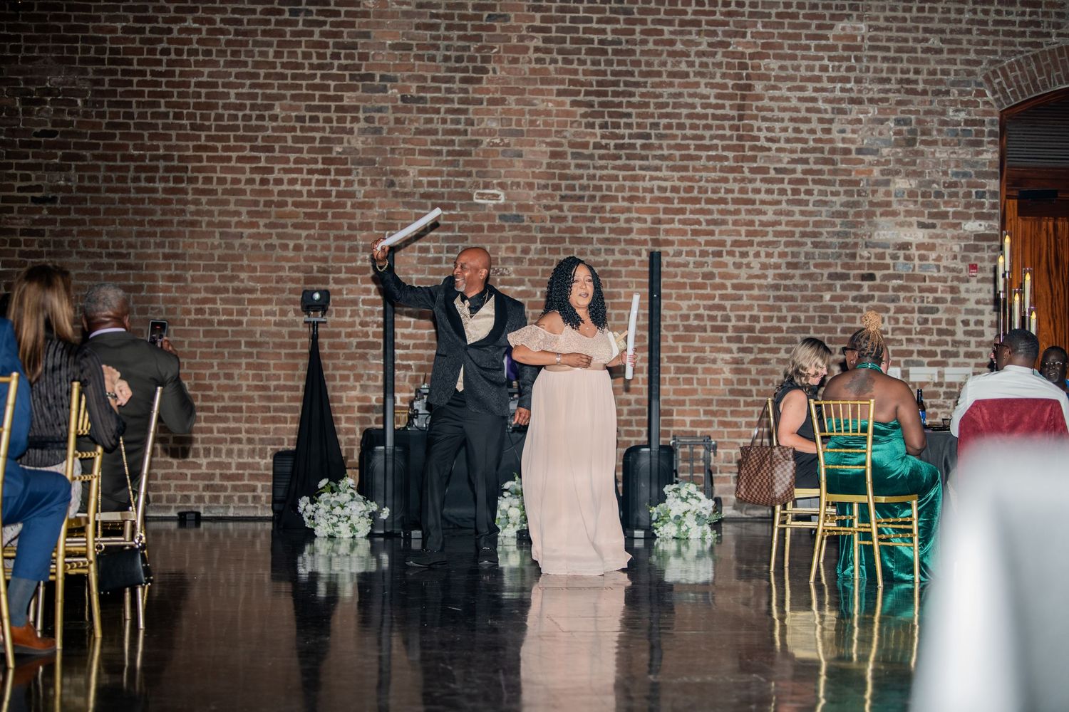 Celebration at a wedding reception with guests dancing in front of exposed brick walls.