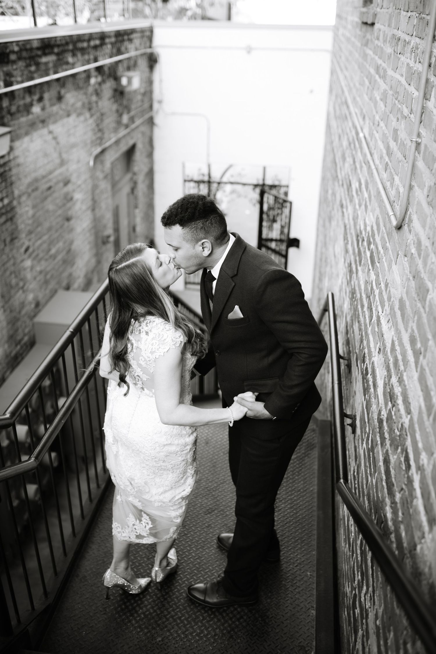 A romantic black and white moment shared between newlyweds on a brick-lined staircase.