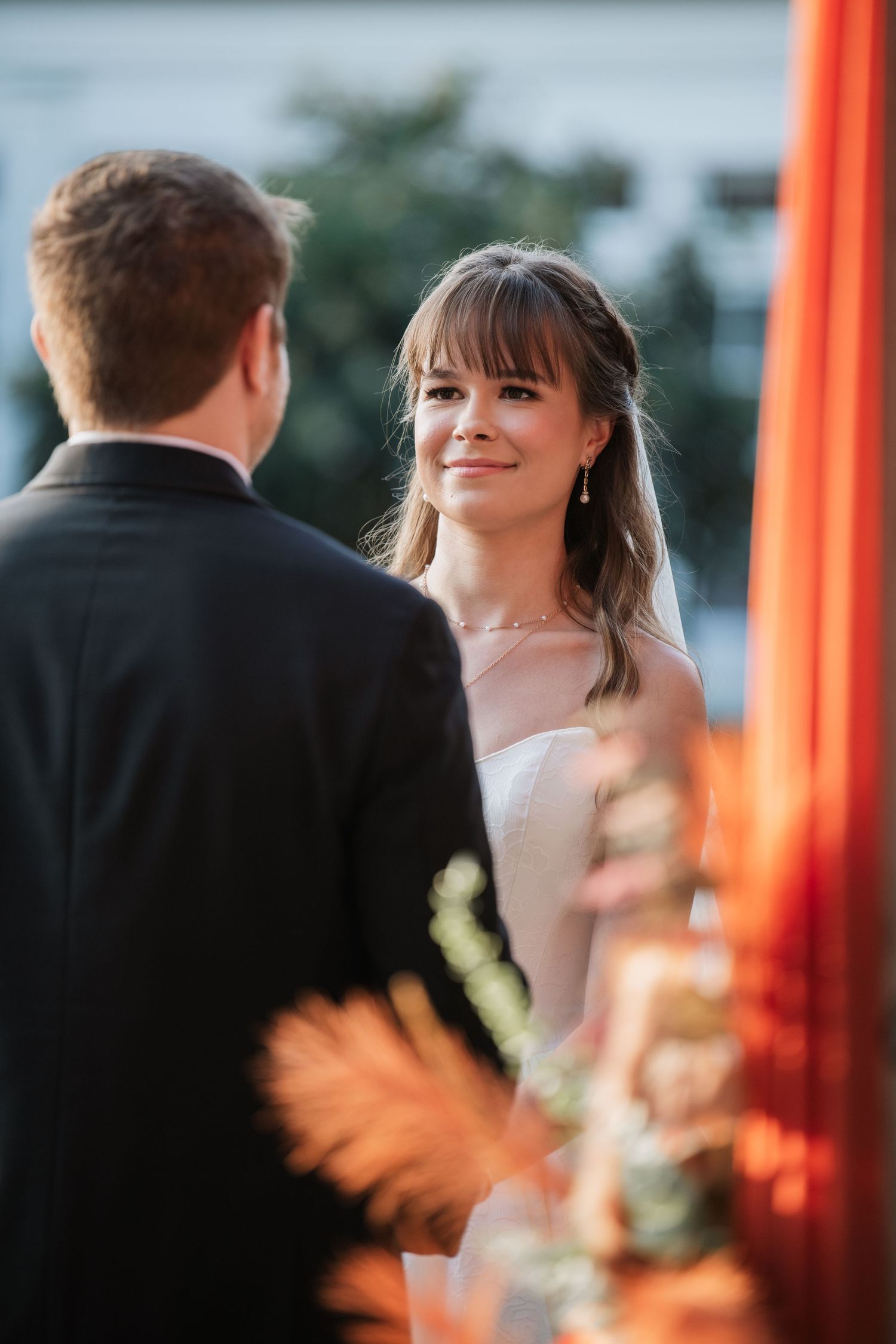 Wedding ceremony under coral drapes with floral accents at dusk.