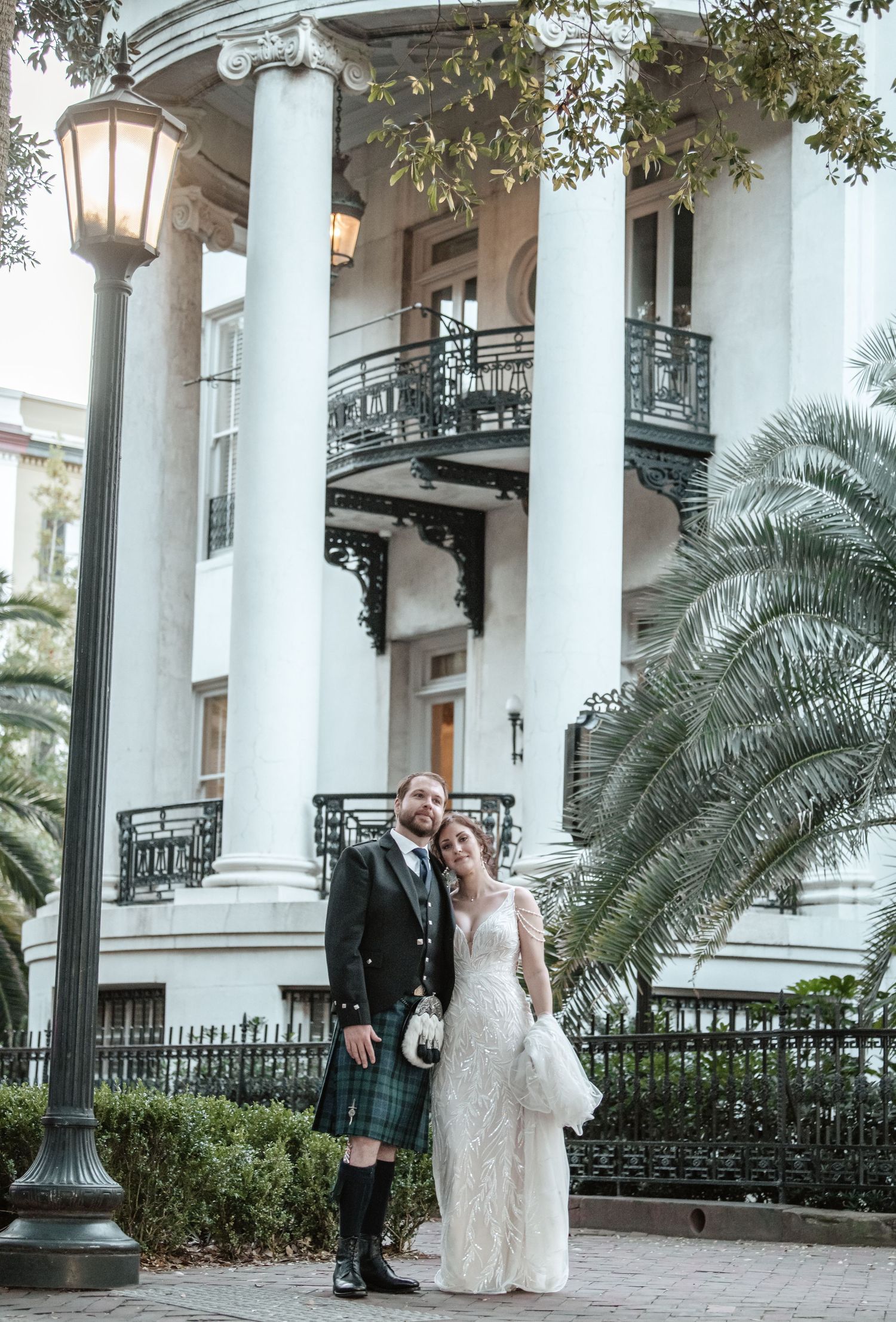 Elegant wedding photos taken at a colonial-style building with white columns and palm trees.